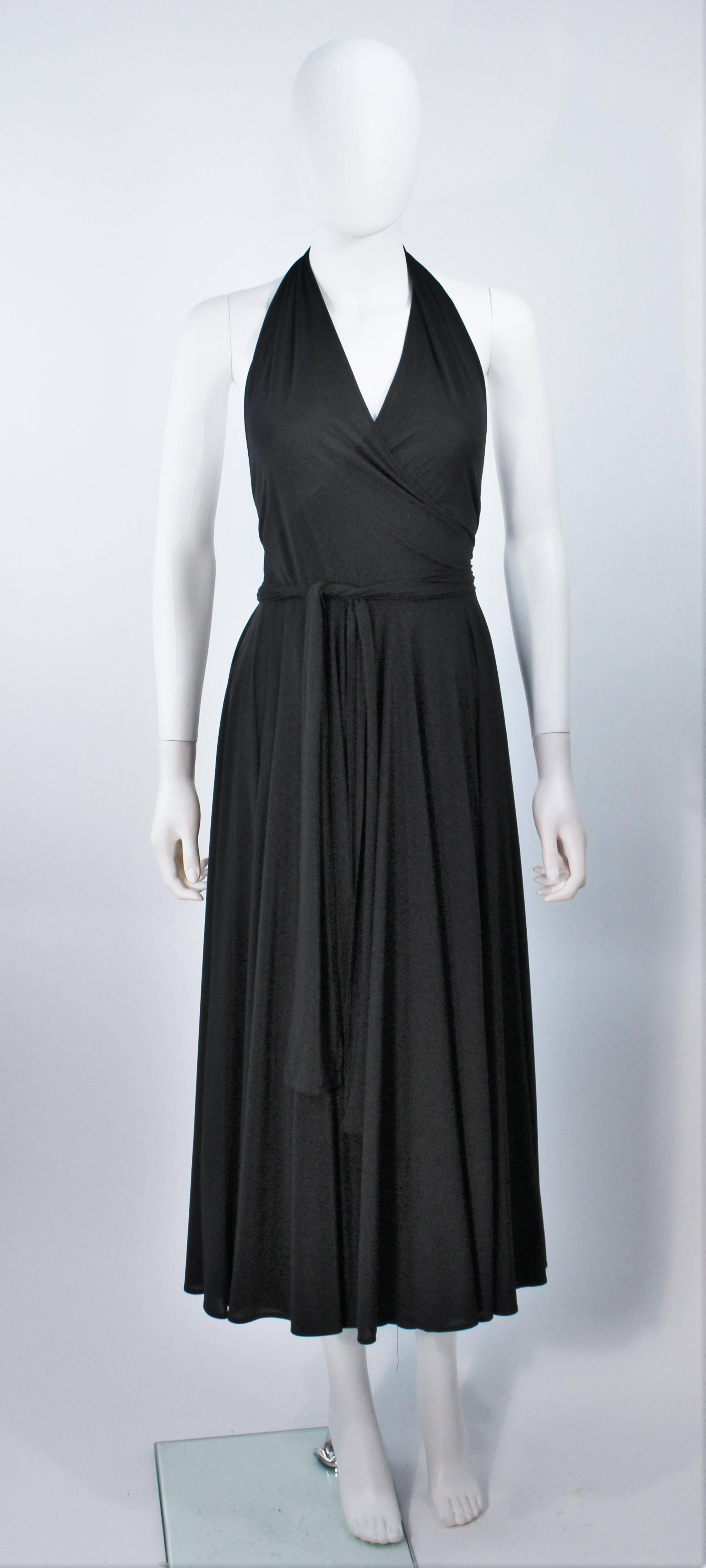  This Norma Kamali  dress is composed of black stretch jersey (polyester) and features a halter neck with wrap style tie. In excellent vintage condition. 

  **Please cross-reference measurements for personal accuracy. Size in description box is