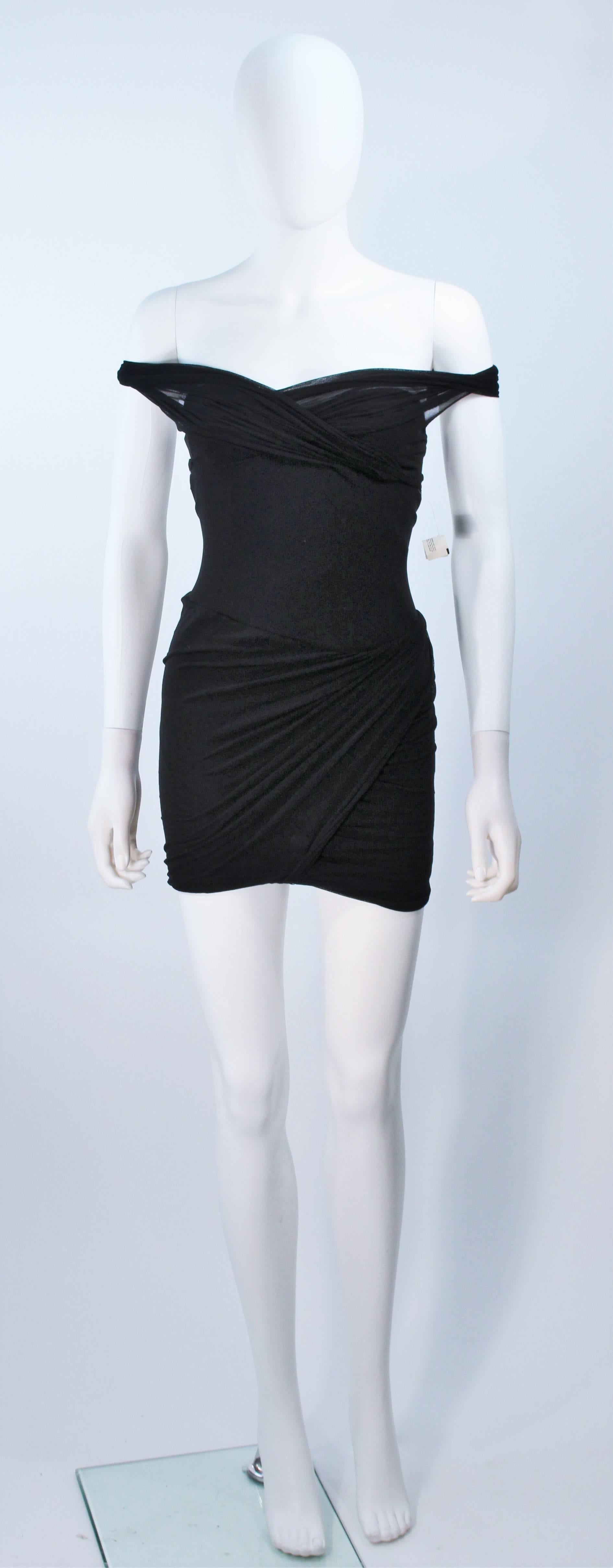  This Giorgio Saint Angelo  dress is composed of a black stretch jersey with mesh over lay in an off the shoulder style. Pull on style. In excellent vintage condition, with original tag. 

  **Please cross-reference measurements for personal