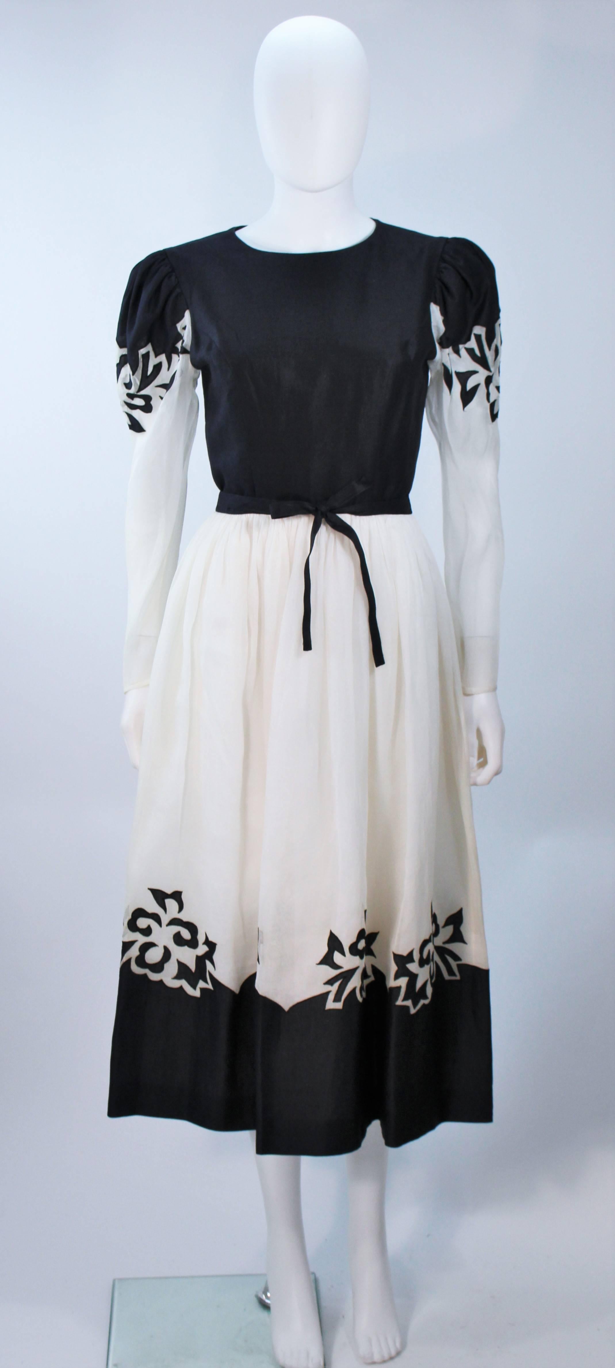  This Albert Nipon  dress is composed of a white and black color blocked fabric with a floral print applique. Features puffed shoulders and sheer sleeves  There is a zipper closure.  In excellent vintage condition. 

  **Please cross-reference