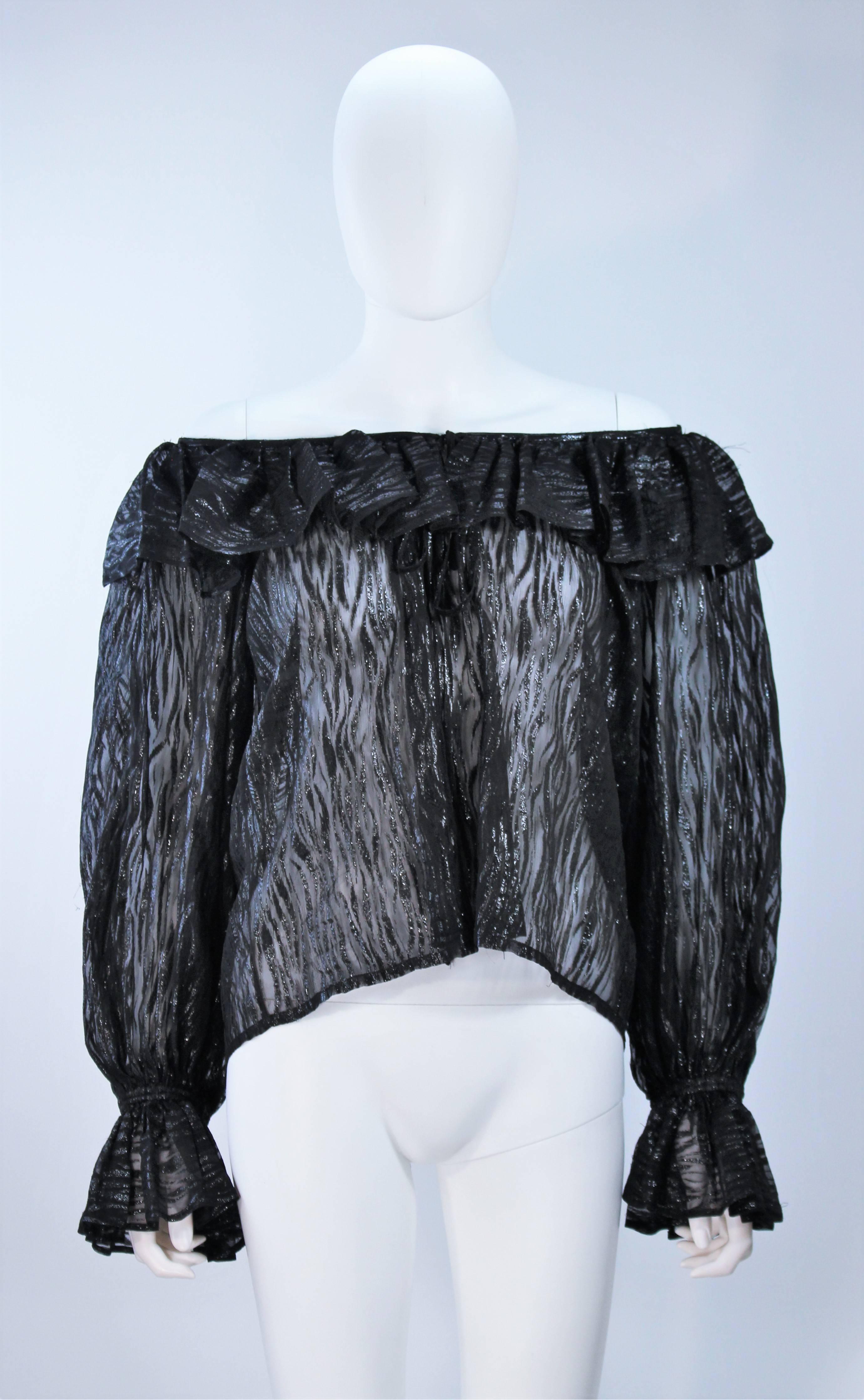  This Yves Saint Laurent blouse is composed of a sheer black printed silk with a textured lame. Features a stretch elastic neckline and sleeves with ruffle accents. Pull over style with tie front. In excellent vintage condition. 

**Please