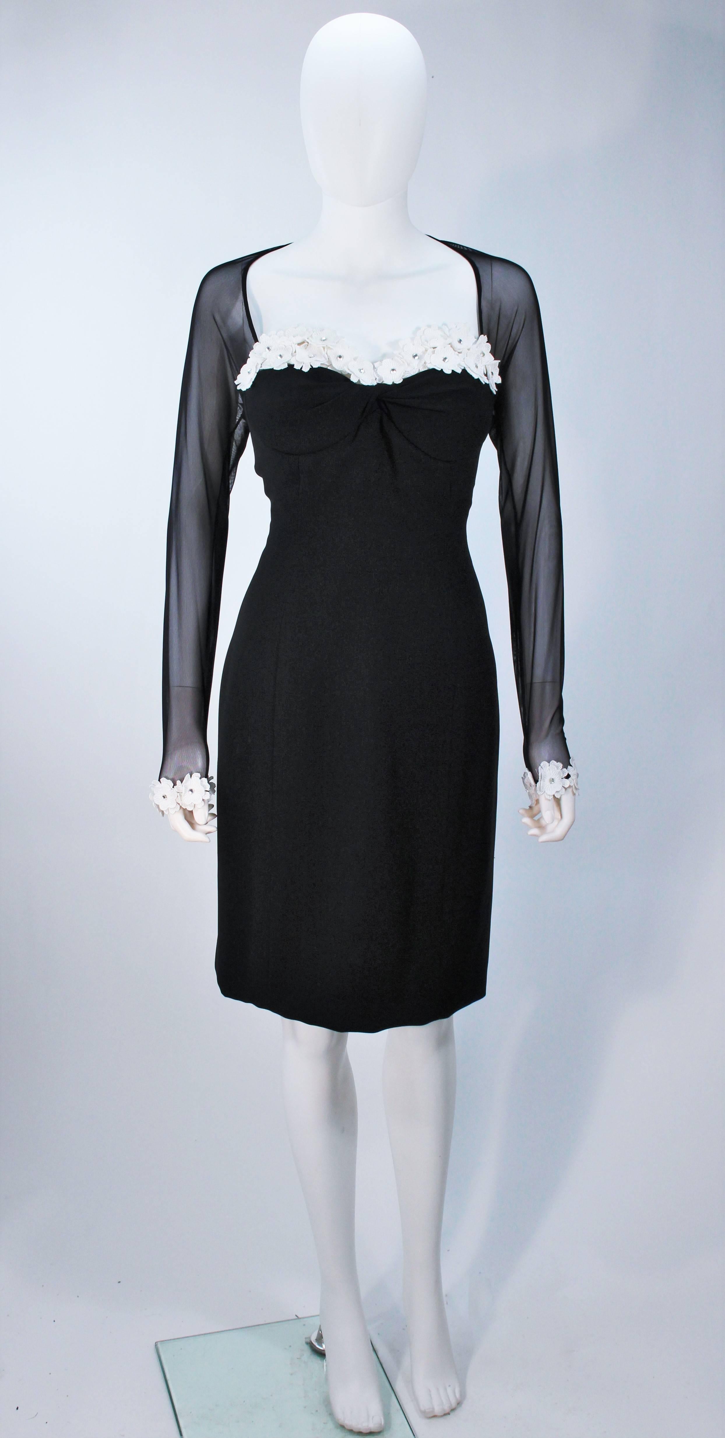  This Travilla  lovely black cocktail dress with long sleeves by Travilla from the 1980's. The Dress has a zipper in the back, floral detail on the front and on the bottom of the Sleeves. The Sleeves are sheer as well as the shoulders and back line.