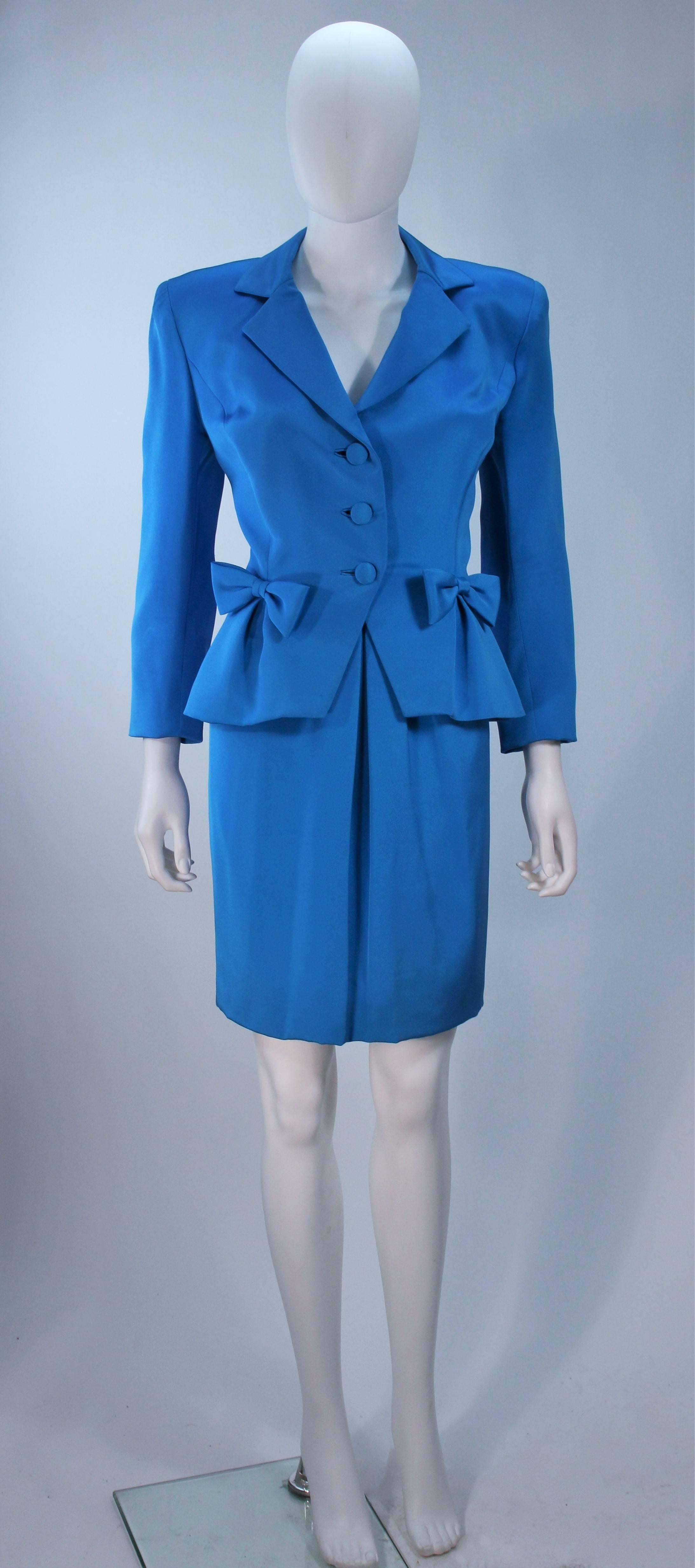  This Travilla  skirt suit is composed of a rich blue silk. The jacket features center front button closures and bow details at the waist. The classic pencil style skirt features a front pleat, there is a side zipper closure. In excellent vintage