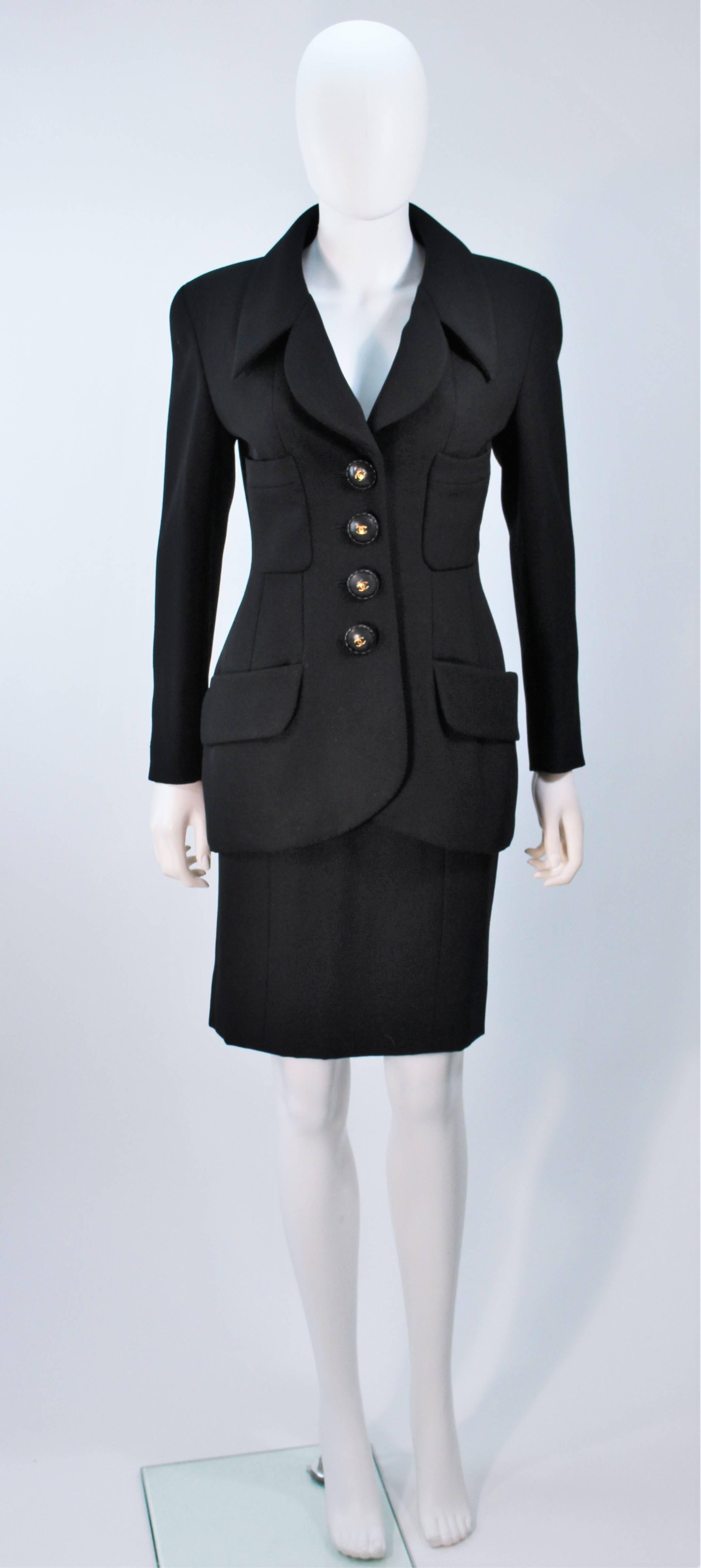  This Chanel skirt suit is composed of a black wool with wood buttons and gold 'CC' logo (silk lining). The jacket features center front button closures and a safari style. The classic pencil style skirt features a zipper closure. In excellent