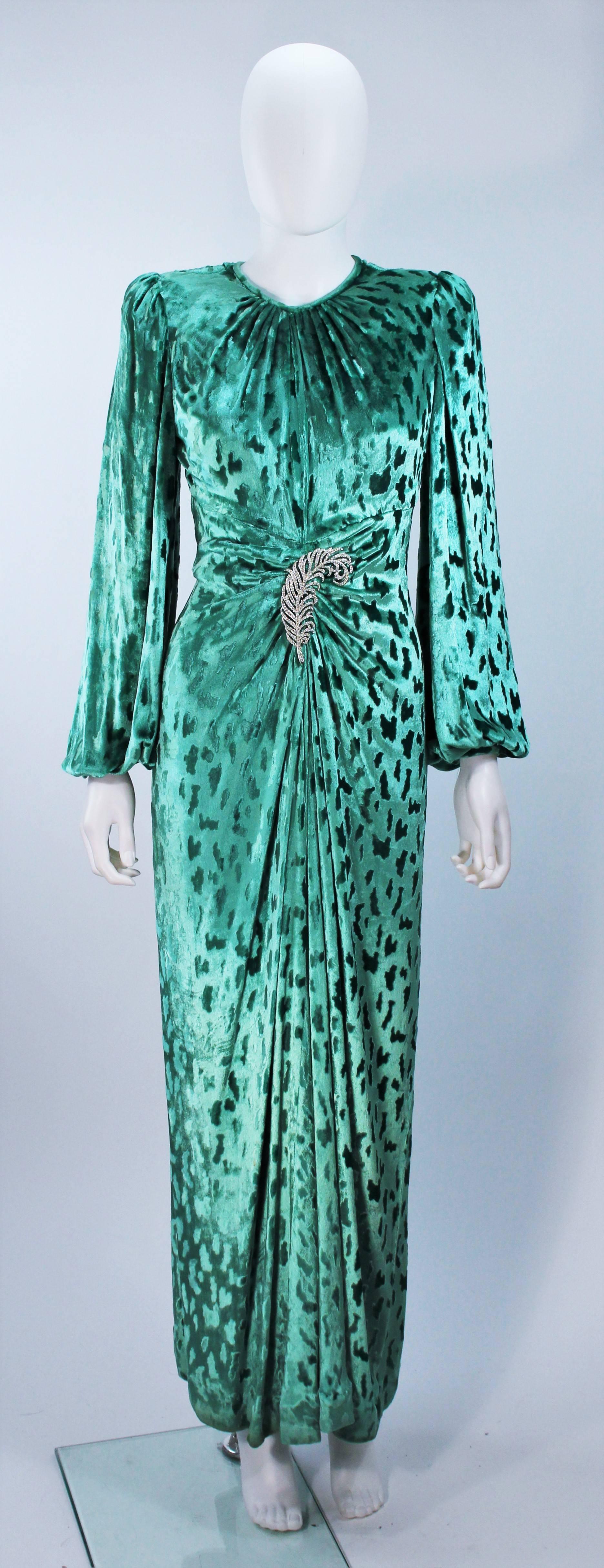  This Oscar De La Renta gown is composed of a mint hue patterned velvet. Features a center front drape with rhinestone brooch at the waist. There are long billow sleeves and a center back zipper closure. In excellent vintage condition. Worn by Nancy