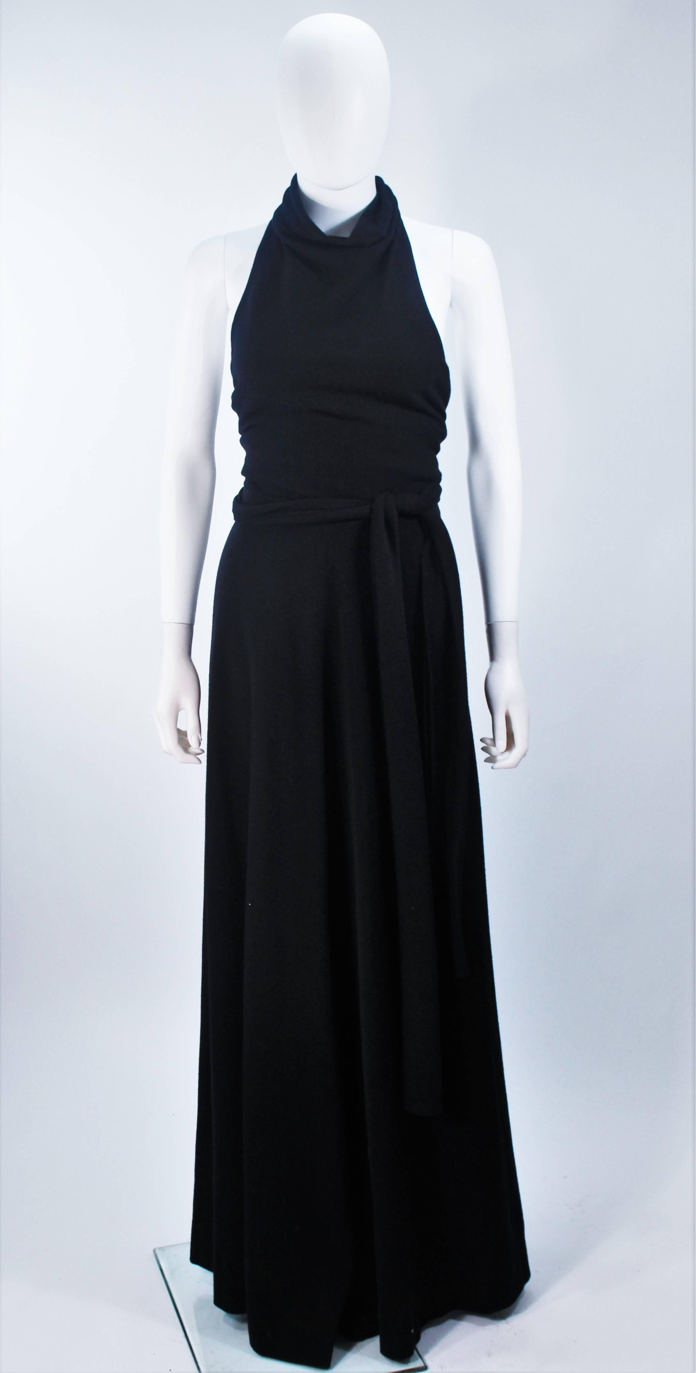  This Jean Patou  dress is composed of a light weight black wool. Features a draped halter style neck with open back, and waist tie. There is a zipper closure. In excellent vintage condition.

  **Please cross-reference measurements for personal