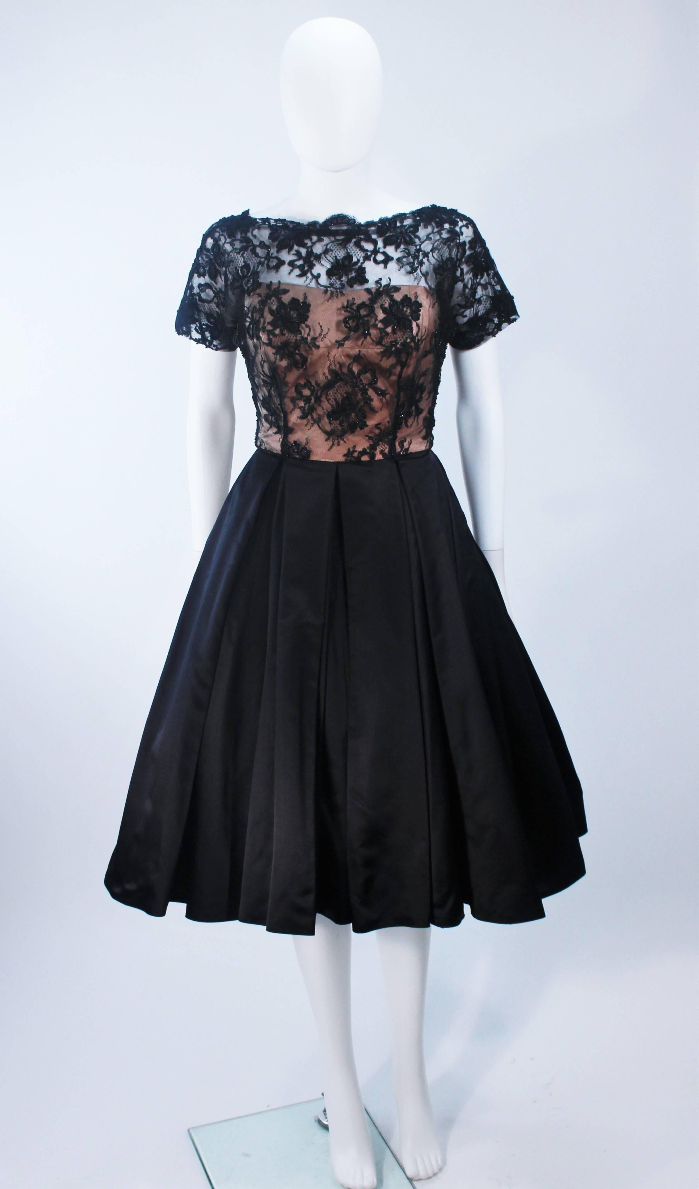  This cocktail dress is composed of black lace with silk. The bodice features scalloped edges with a nude underlay. The skirt is shot with crinoline (not included). There is a zipper closure with hook and eyes. In excellent vintage condition. 

 