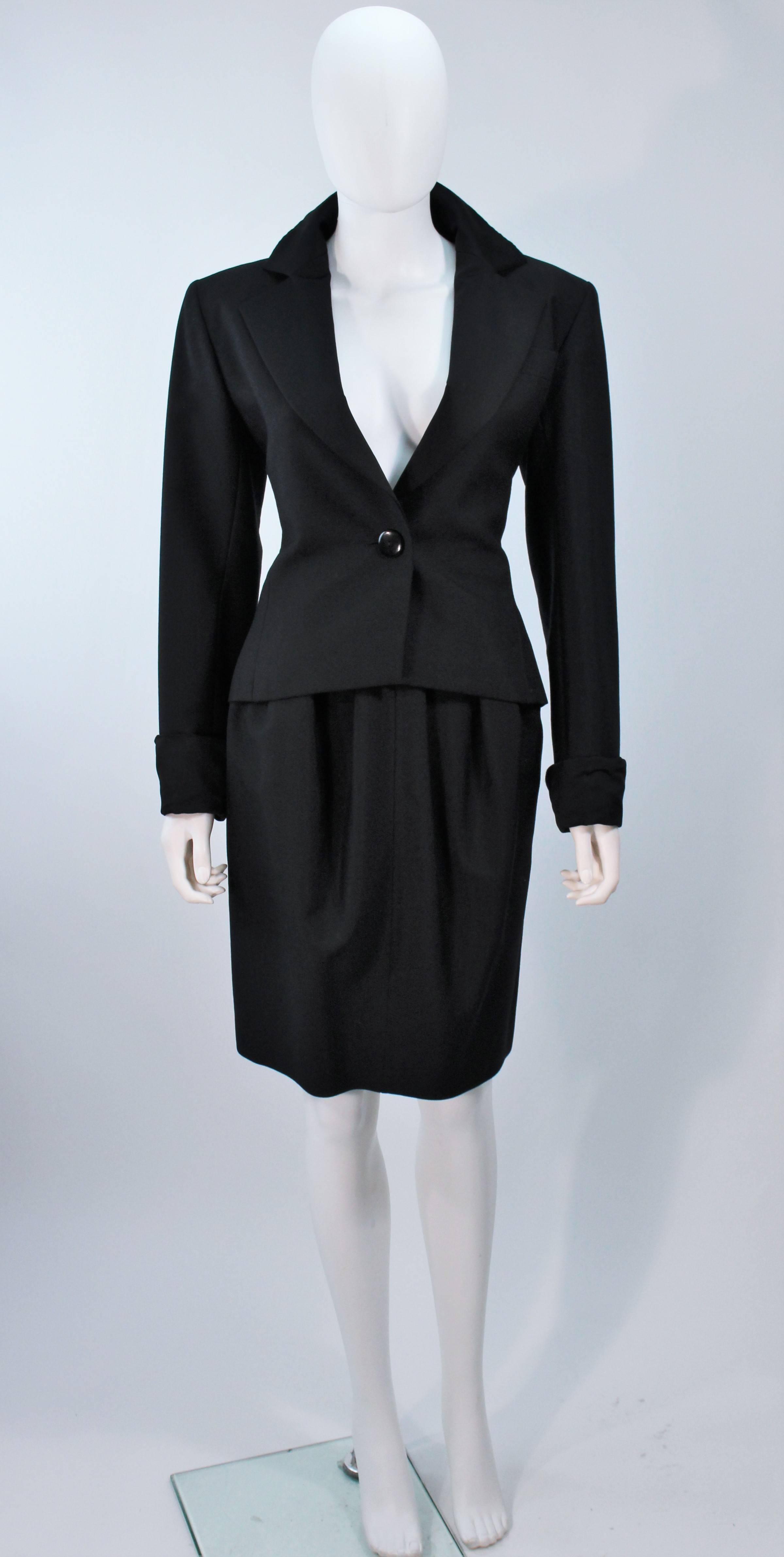  This Yves Saint Laurent skirt suit is composed of a black wool with satin trim. The jacket features a center front button closure. The skirt has a zipper closure with side pockets, and pleated front detail. In excellent vintage condition. 

 