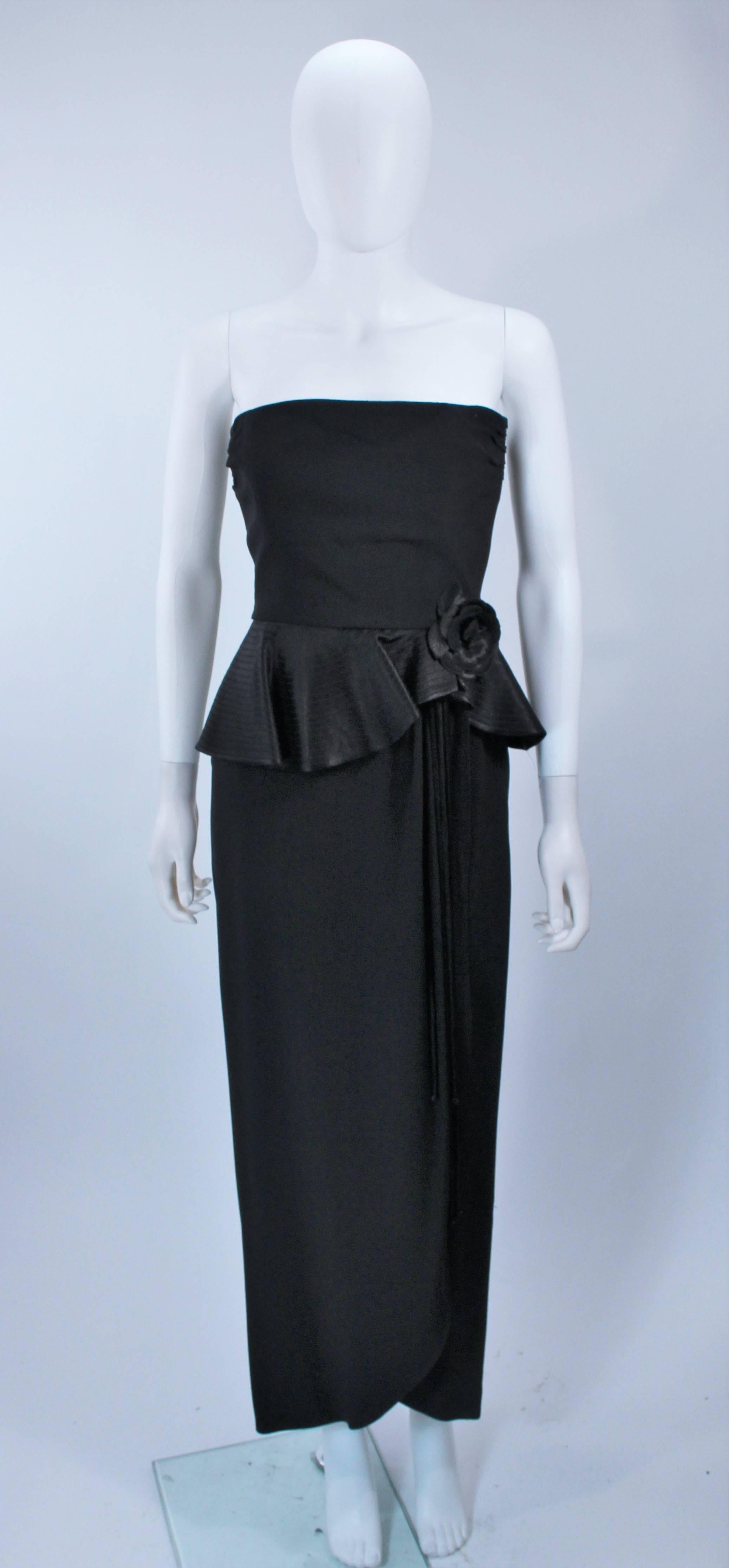  This Albert Nipon gown is composed of a black crepe textured fabric. Features a strapless design with top stitch satin peplum and draped rose detail There is a center back zipper closure and button accents. In excellent vintage condition. 

 