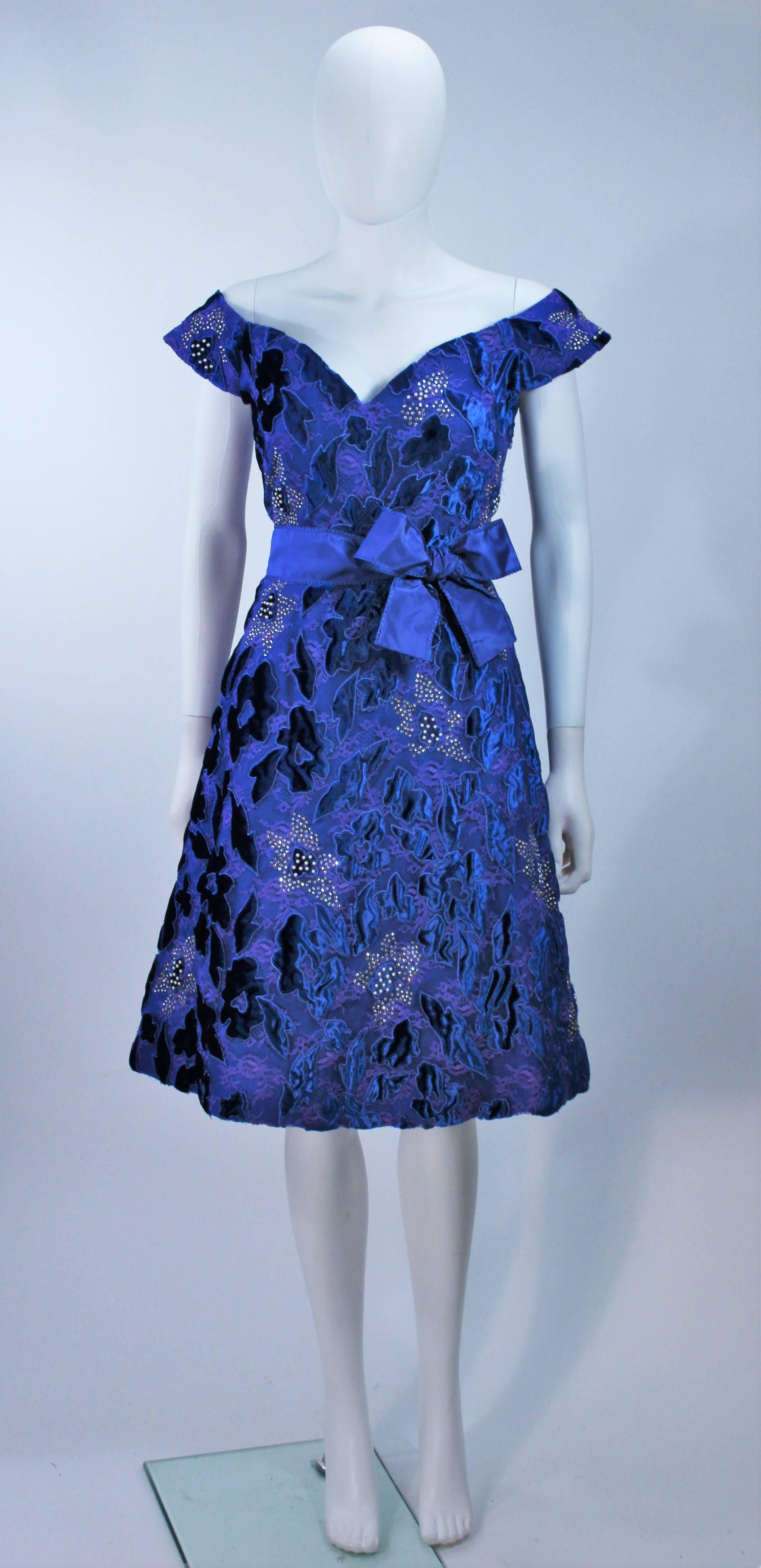  This Arnold Scaasi cocktail dress is composed of a blue velvet and satin combination, with a floral pattern and rhinestone applique. There is a center back zipper closure. (photographed with crinoline, not included). In excellent vintage condition.
