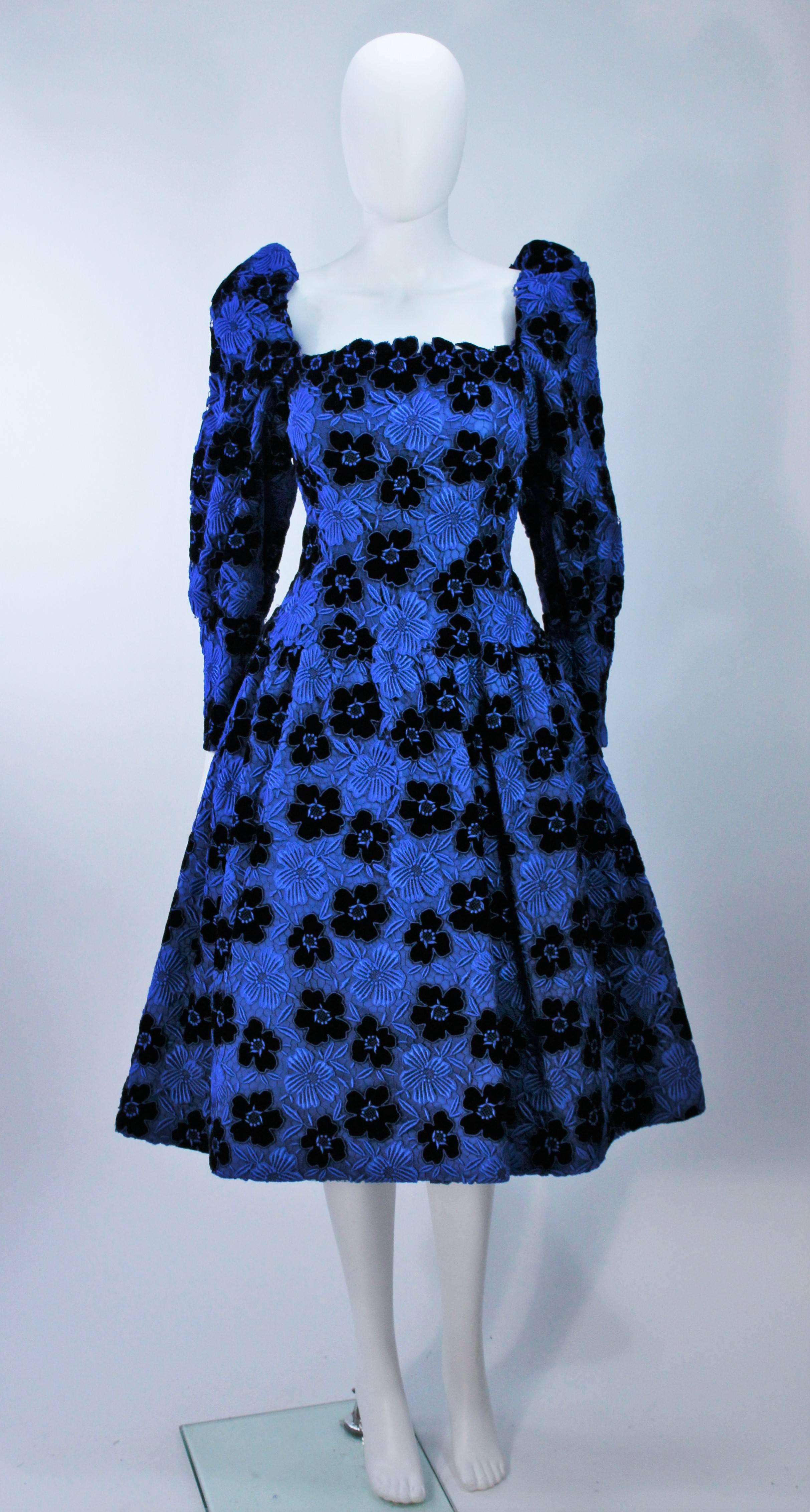  This Arnold Scaasi  cocktail dress is composed of a blue velvet and satin combination, with a floral pattern. There is a center back zipper closure with snaps. (photographed with crinoline, not included). In excellent vintage condition. 

 