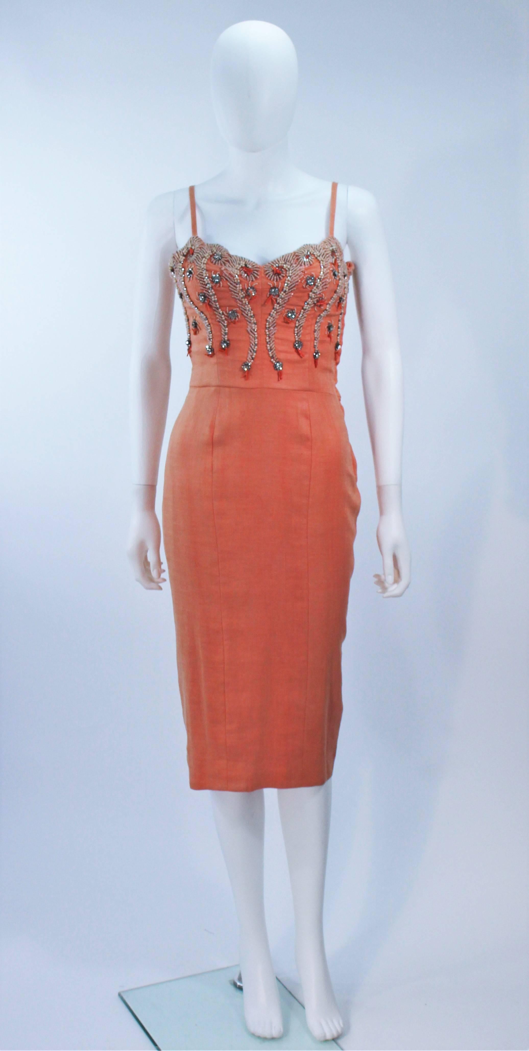  This cocktail dress is composed of a coral hue linen with a beaded applique (Rhinestones, faux pearls, beads). There is a center back zipper closure. In excellent vintage condition, color variation of fabric due to age. 

  **Please