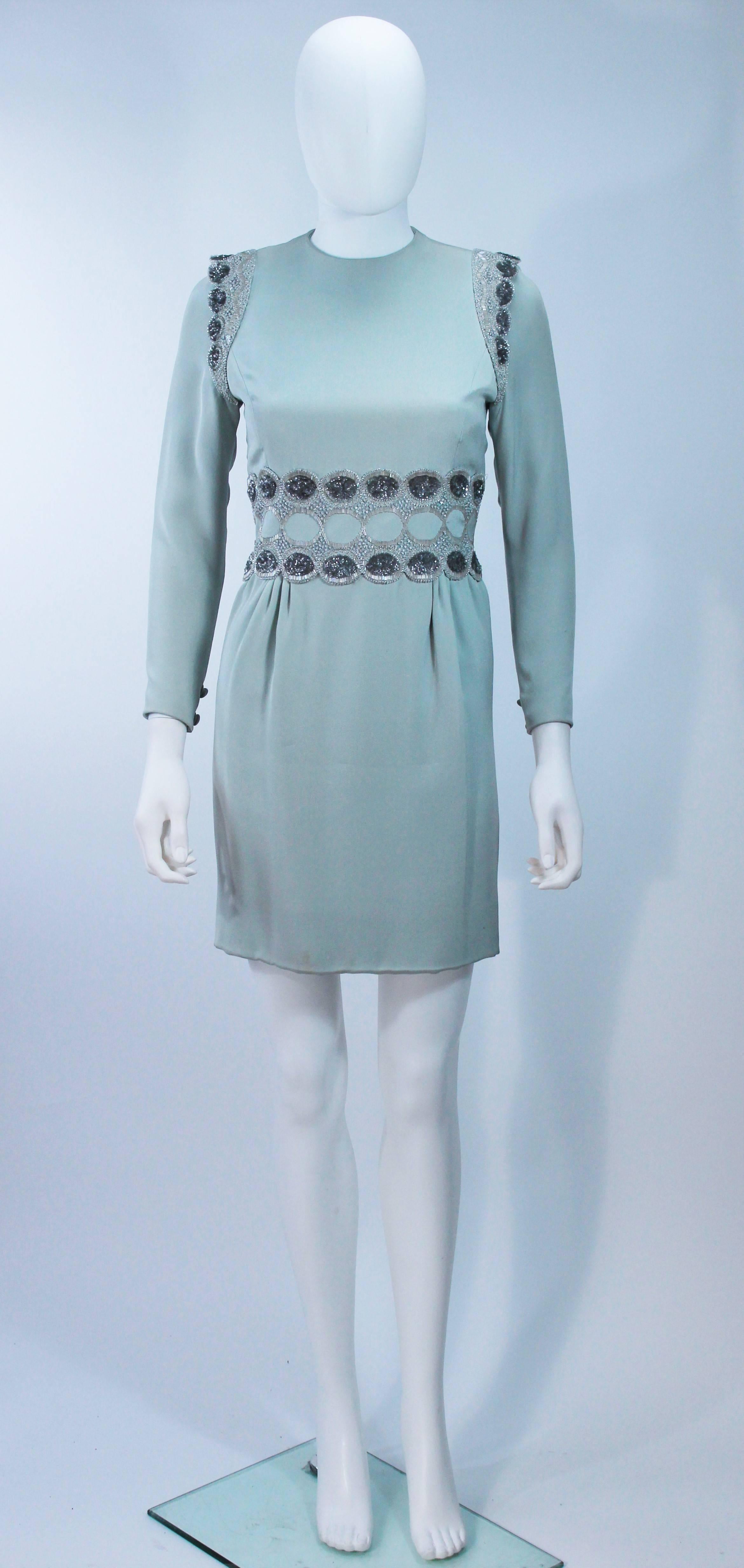  This cocktail dress is composed of a blue fabric with beading at the shoulders and waist. There is a center back zipper closure, and shoulder pads. In excellent vintage condition, slight color variation with fabric due to age. 

  **Please