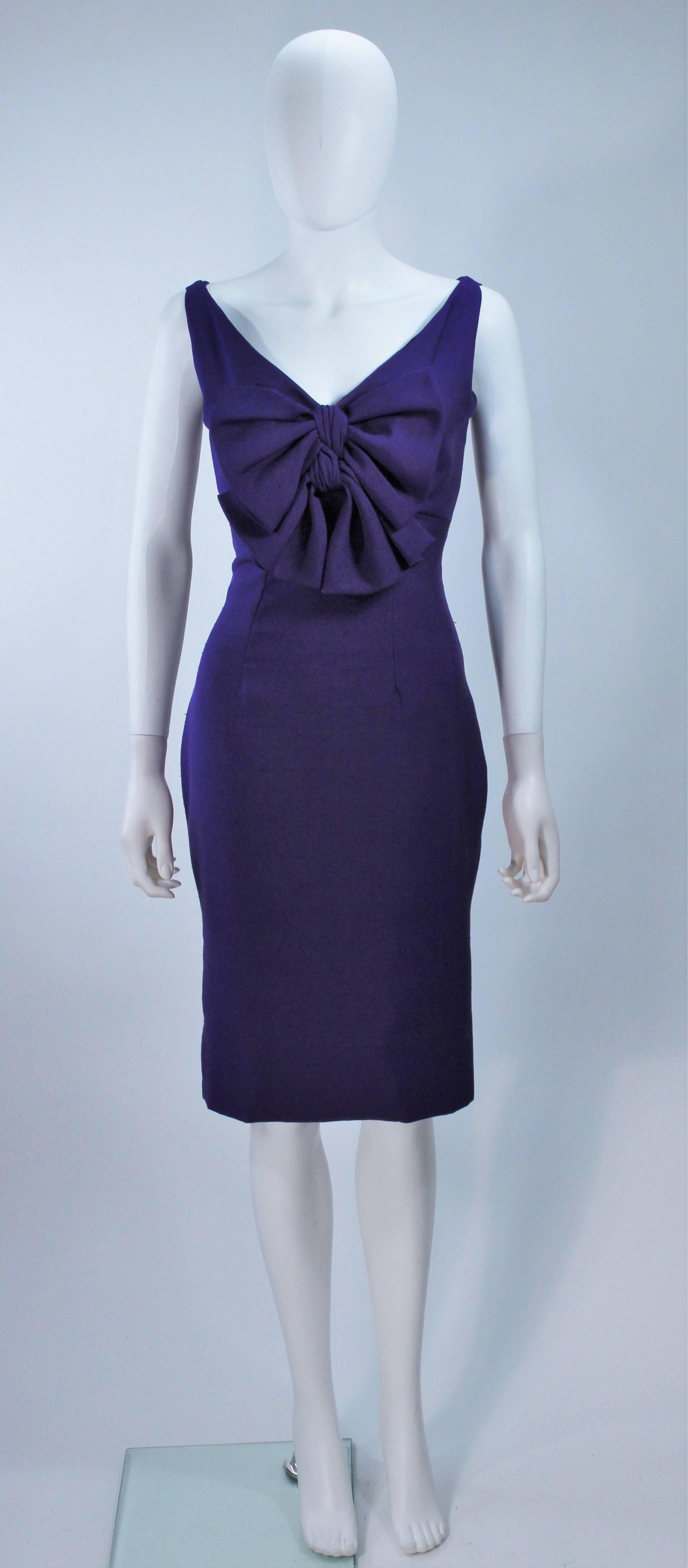 This Elizabeth Mason Couture sleeveless purple silk dupioni dress features a large center front bow. It is lined with silk and has a center back zipper. Made in Beverly Hills. 

This is a couture custom order. Please allow for a 60 day lead time