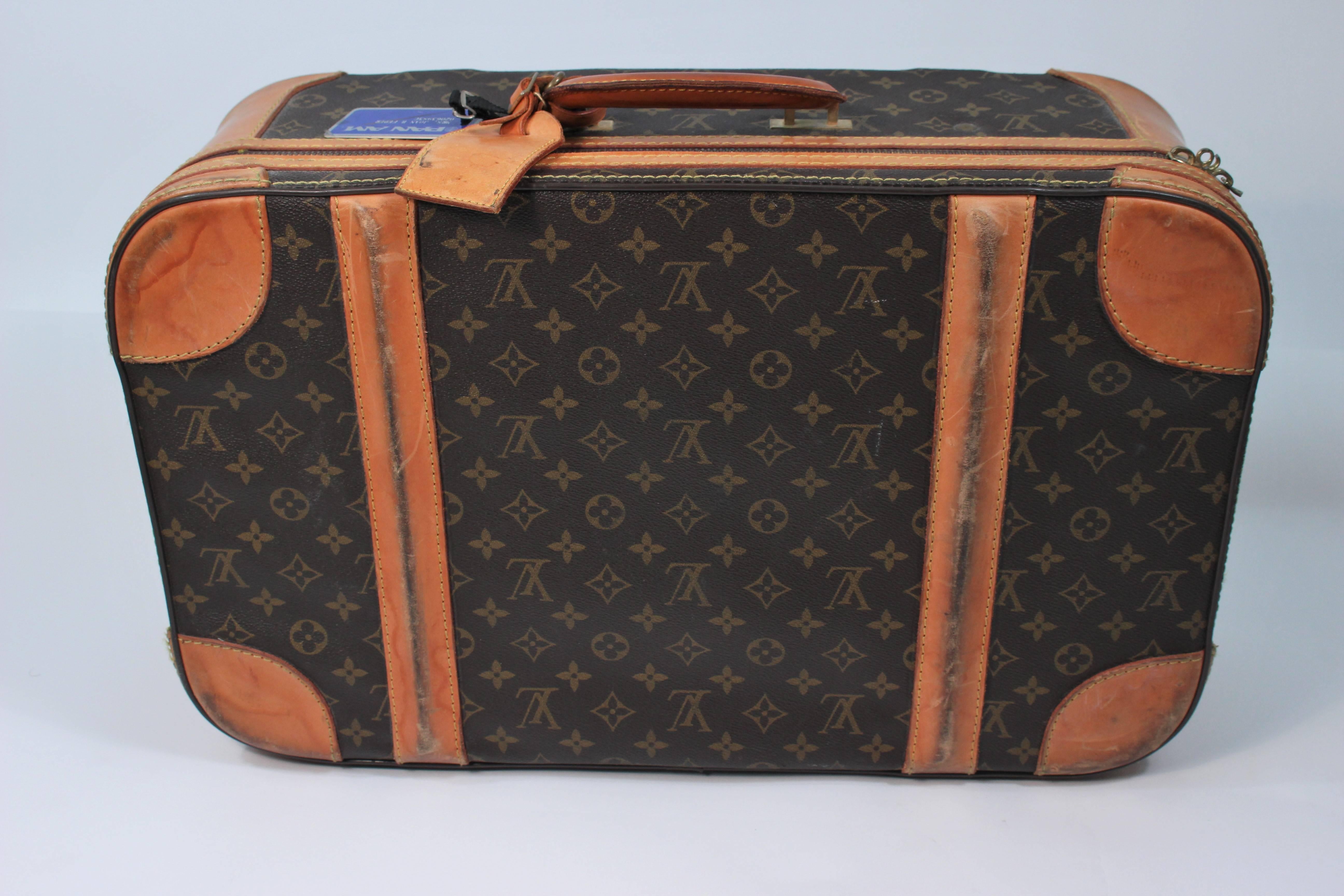 This vintage Louis Vuitton luggage  features the classic monogram style print and gold hardware. In vintage sold 'As is' condition, shows signs of wear on leather, hardware is aged (see photographs), locking part of the zipper pulls is broken. Clean