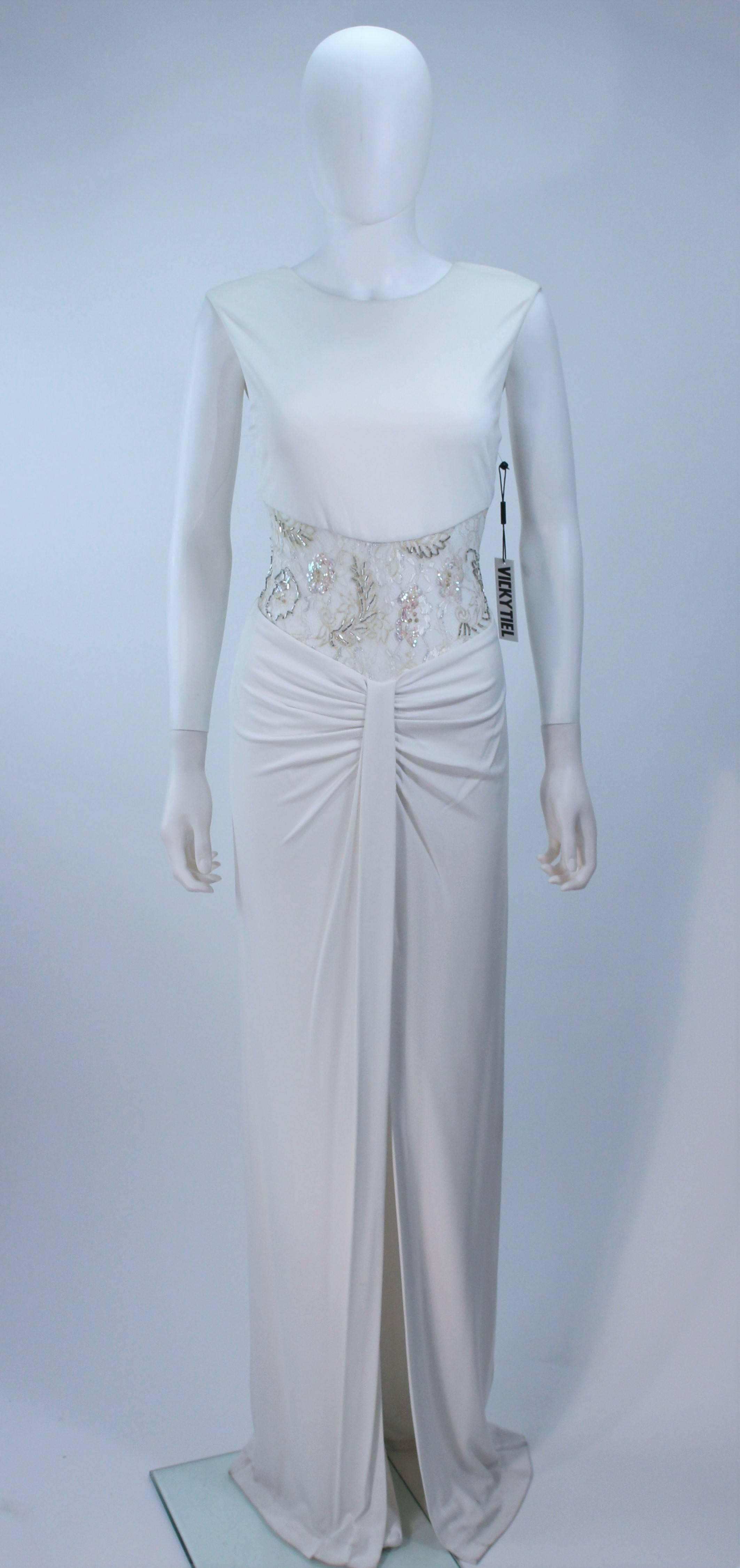  This Vicky Tiel  gown is composed of a draped jersey. Features a sheer lace bodice with sequin applique. There is a center back zipper closure with buttons. In great vintage condition. 

  **Please cross-reference measurements for personal