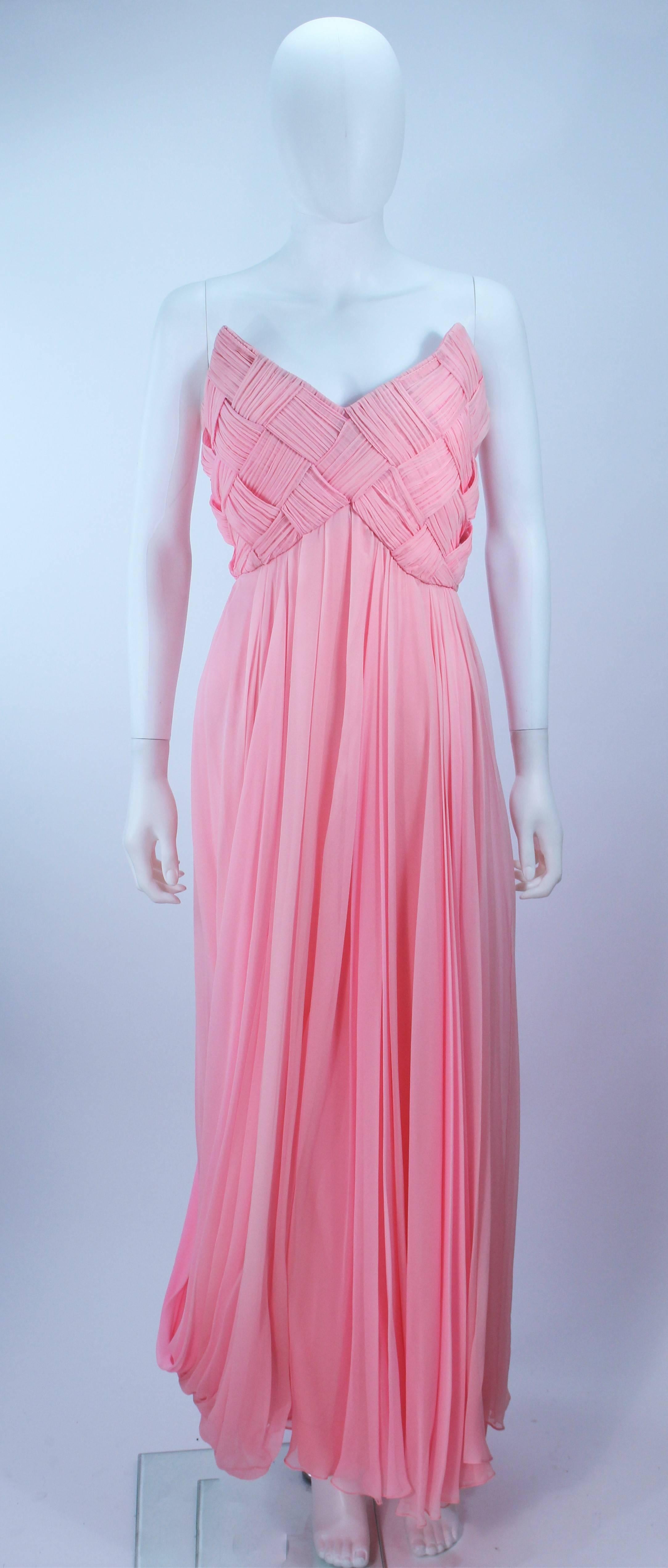 This Scaasi  gown is composed of a pink chiffon. The bodice has a criss-cross design. The skirt features a drape style. There is a center back zipper closure with bow accent. In very good condition with some minor fading.

  **Please cross-reference