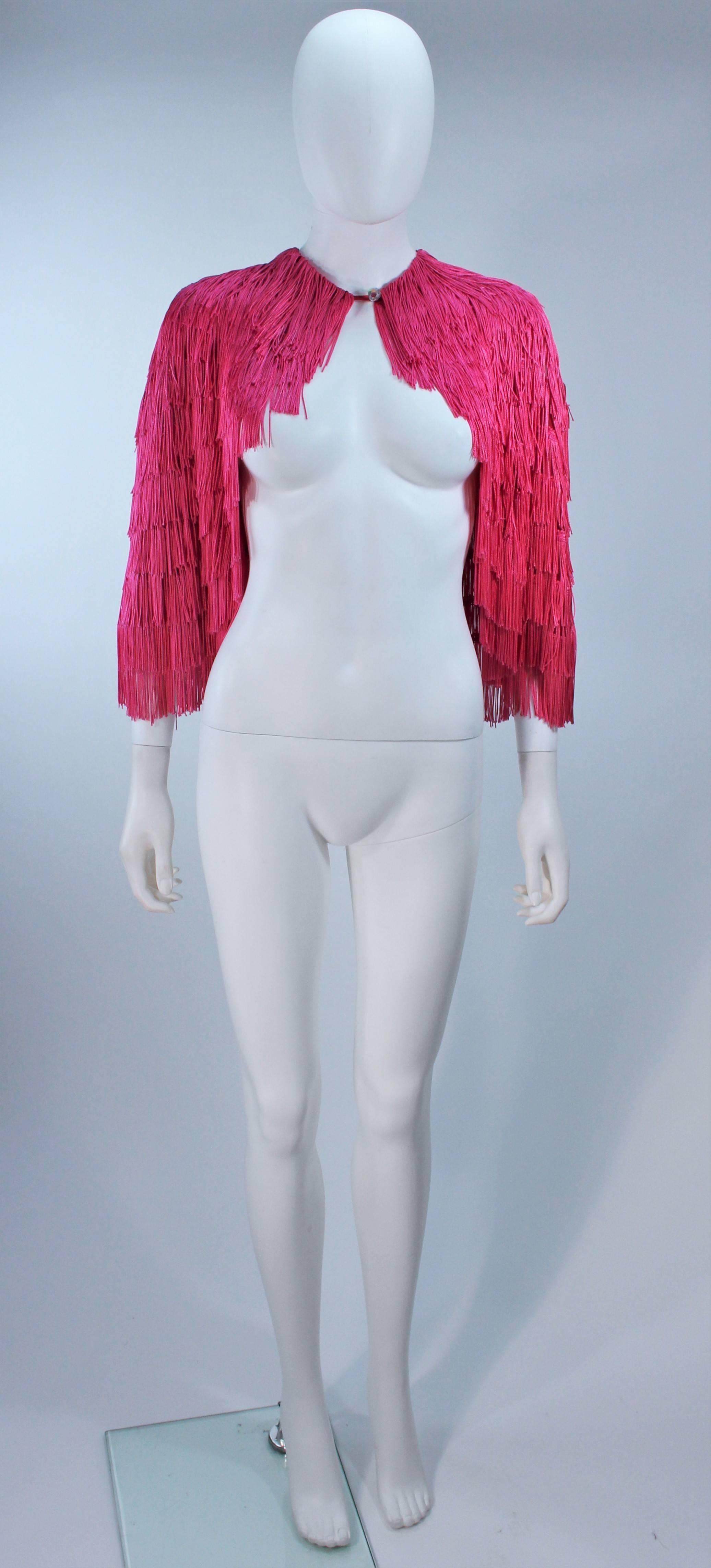 This Elizabeth Gillet cape is composed of a pink fringe over top a sheer mesh. There is a iridescent faceted button closure. In excellent condition.

  **Please cross-reference measurements for personal accuracy. 

Measures