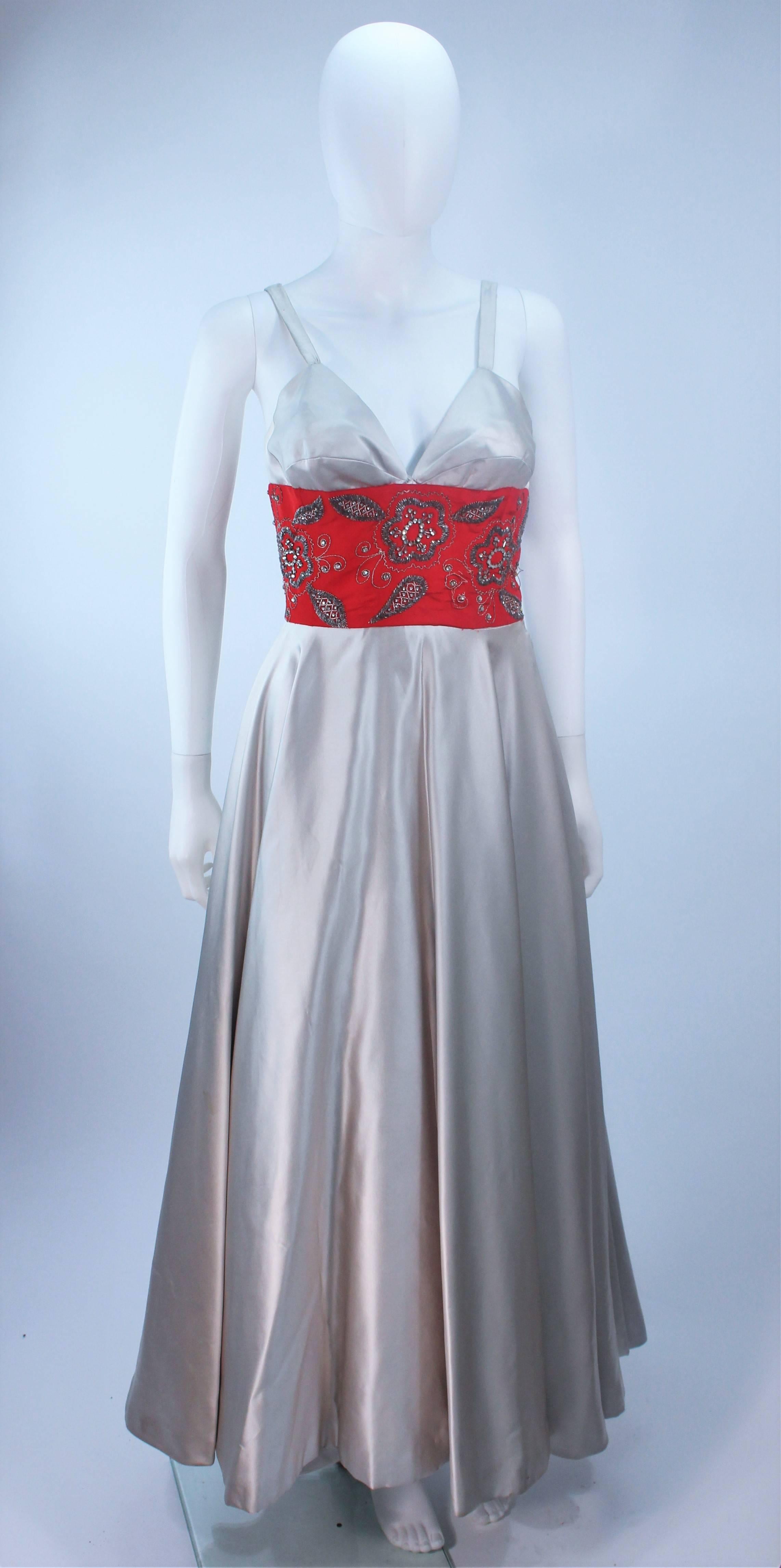 This Eleanora Garnett  gown is composed of a silver silk with a red embellished waist. Features a darted style bust. There is a side zipper closure. In excellent vintage condition. (Shot with crinoline and tissue in the bust).

  **Please