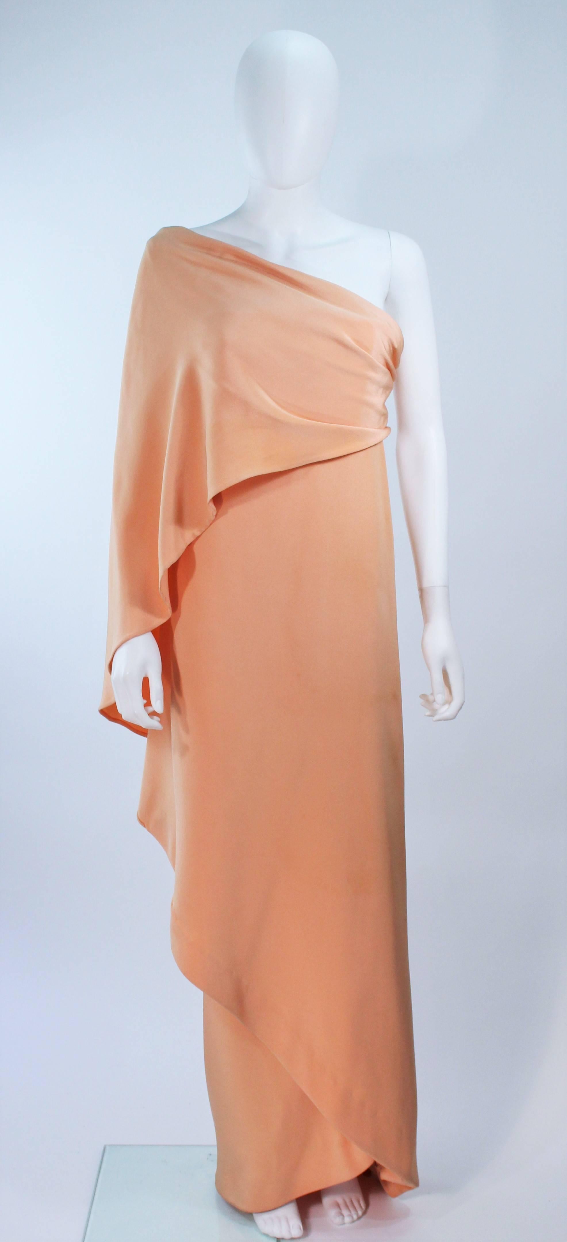 This is a vintage long peach silk gown by Givenchy, from the 1970's. The gown has a constructed bodice and a draped sleeve over the shoulder. There is some discoloration due to age. Features interior boned bustier 

Provenance: Betsy