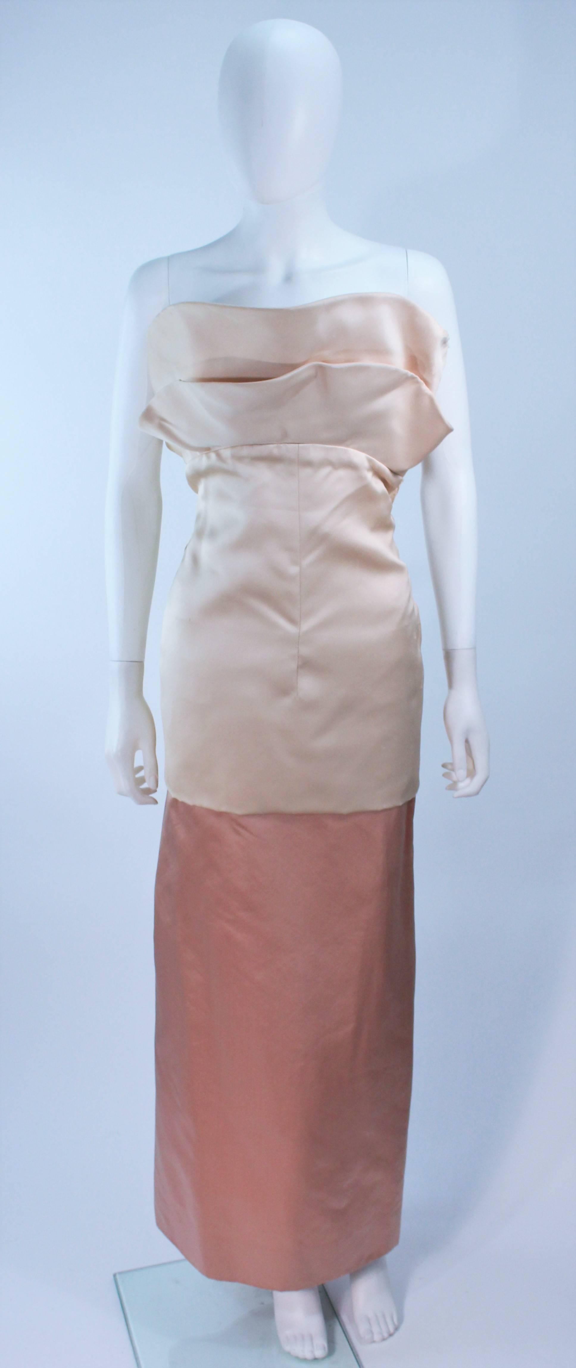 This is a DESIGN STUDY piece, and is being sold as such only. 
There is some deterioration of the silk at the edges and one of the large back buttons missing.

Pauline Trigere strapless gown 
champagne and peach silk satin 
Flounce Flower at bust