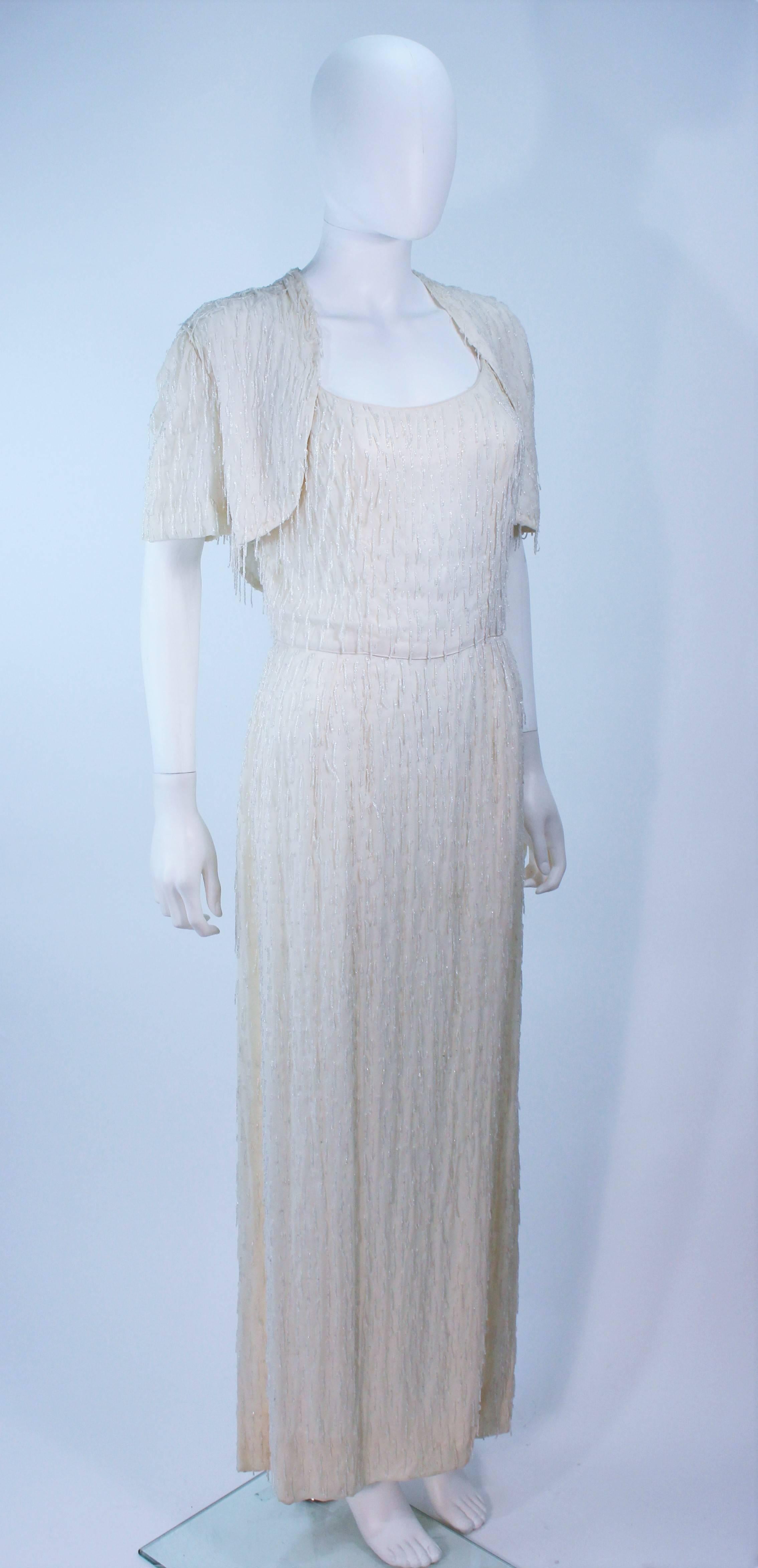  This ensemble is composed of a beaded crepe silk with a clear fringe style beading. Features a bolero style jacket and gown. There is a center back zipper In excellent vintage condition.

  **Please cross-reference measurements for personal