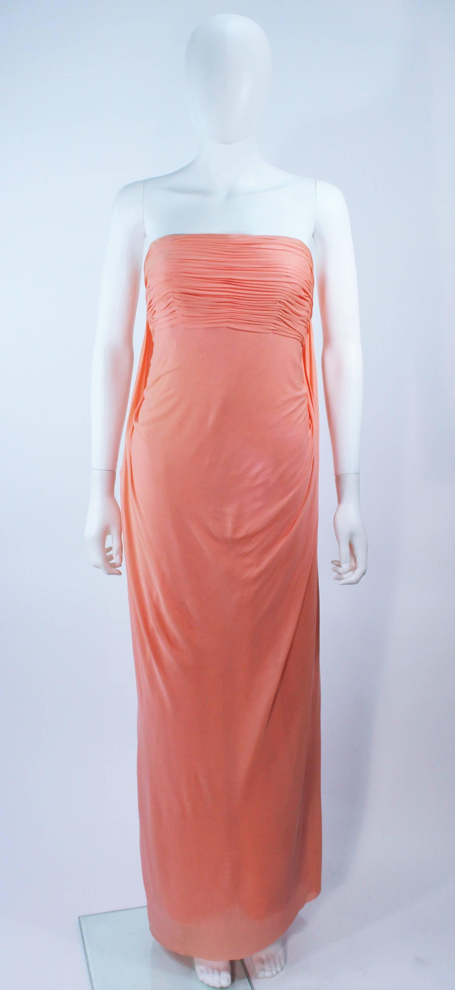 This Travilla  gown is composed of a peach jersey. Features a draped style with interior bustier and zipper closure. In good vintage condition, there is discoloration and signs of wear on the fabric (best for design research).

  **Please