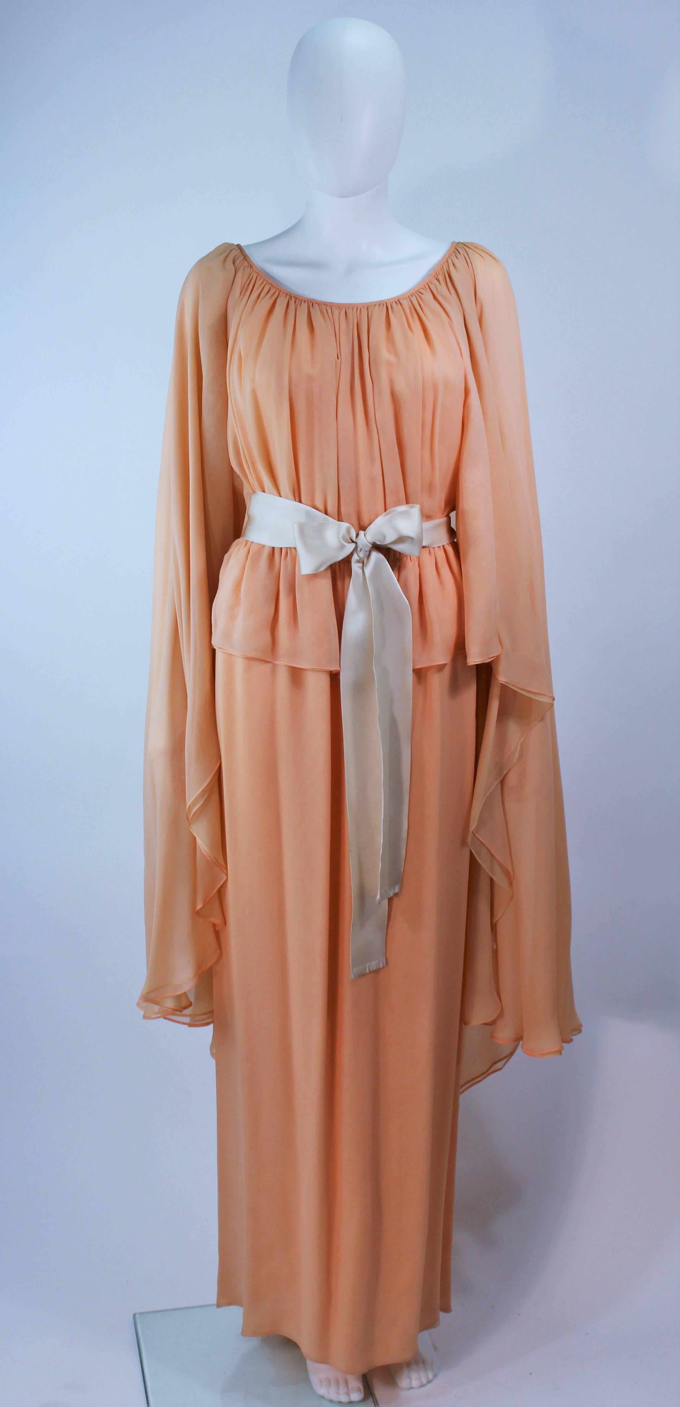 This Bonwit Teller own is composed of a peach and apricot hue silk with a draped design, and satin belt. There is a center back closure. In excellent condition, some slight color discoloration.

  **Please cross-reference measurements for personal