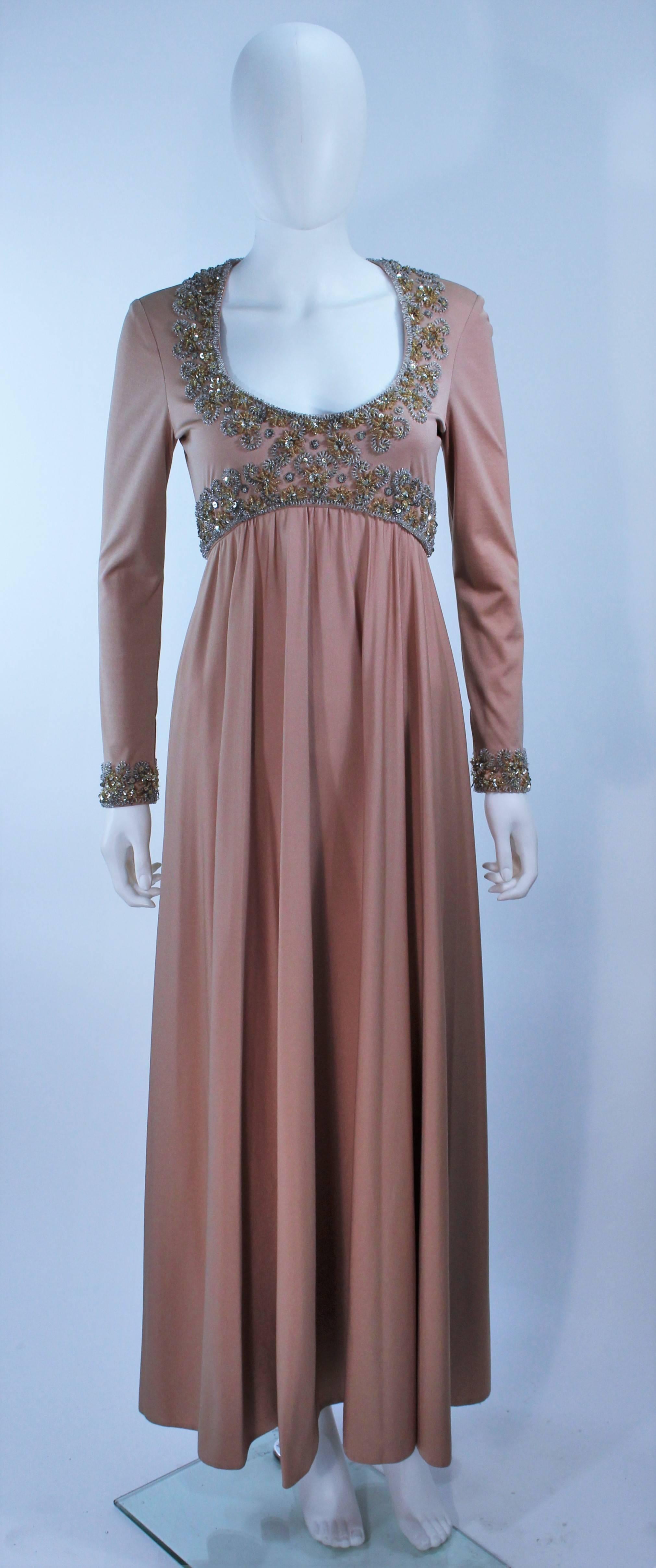  This gown is composed of a toffee hue jersey with a beaded applique on the bust and sleeves. Features a draped design with a center back zipper closure, and hook & eyes at the sleeve end. In excellent vintage condition.

  **Please