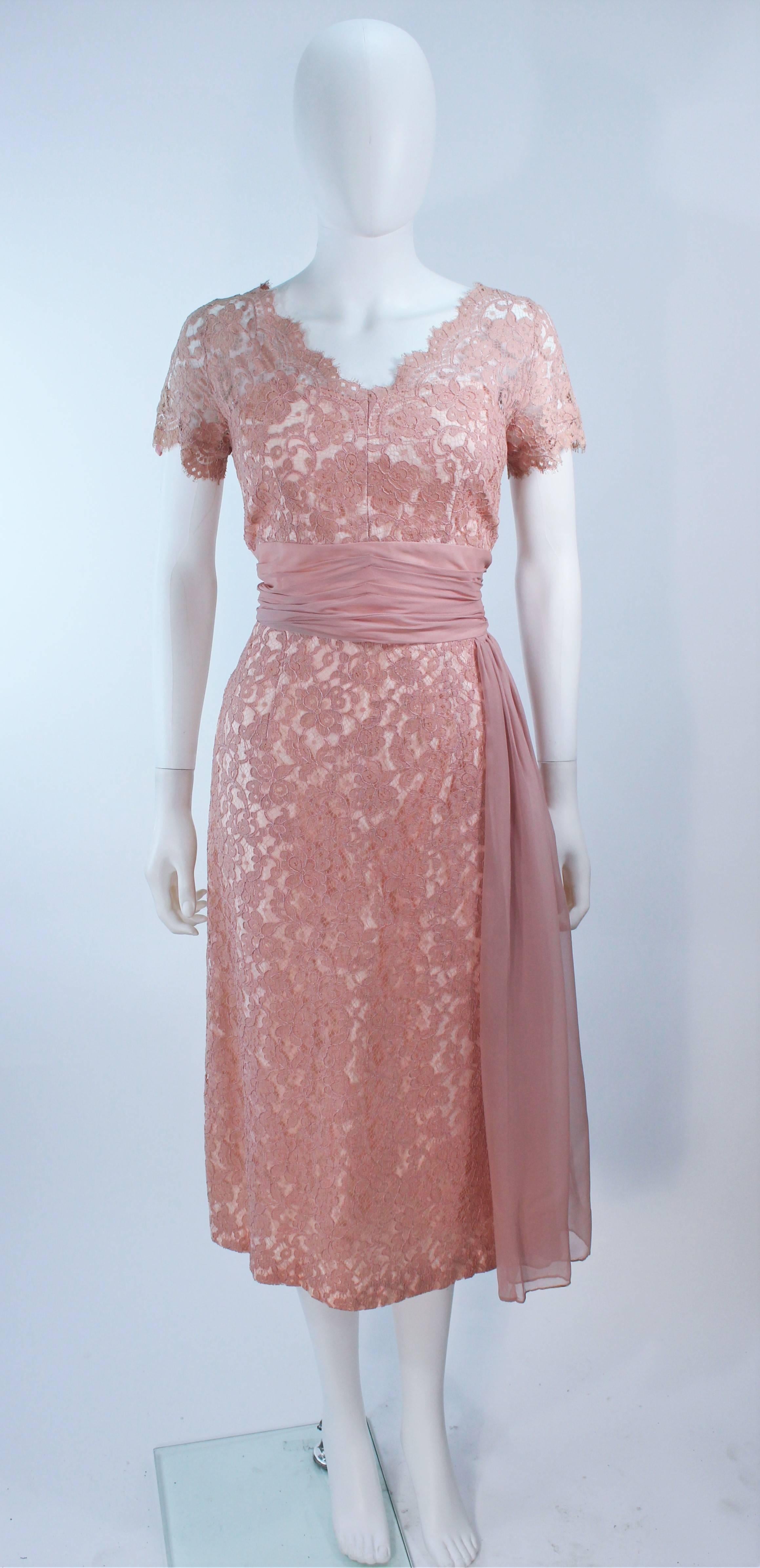  This cocktail dress is composed of a peach hue lace with scalloped edges. Features a gathered chiffon waist and drape. Satin lining. There is a center back zipper closure. In great vintage condition.

  **Please cross-reference measurements for