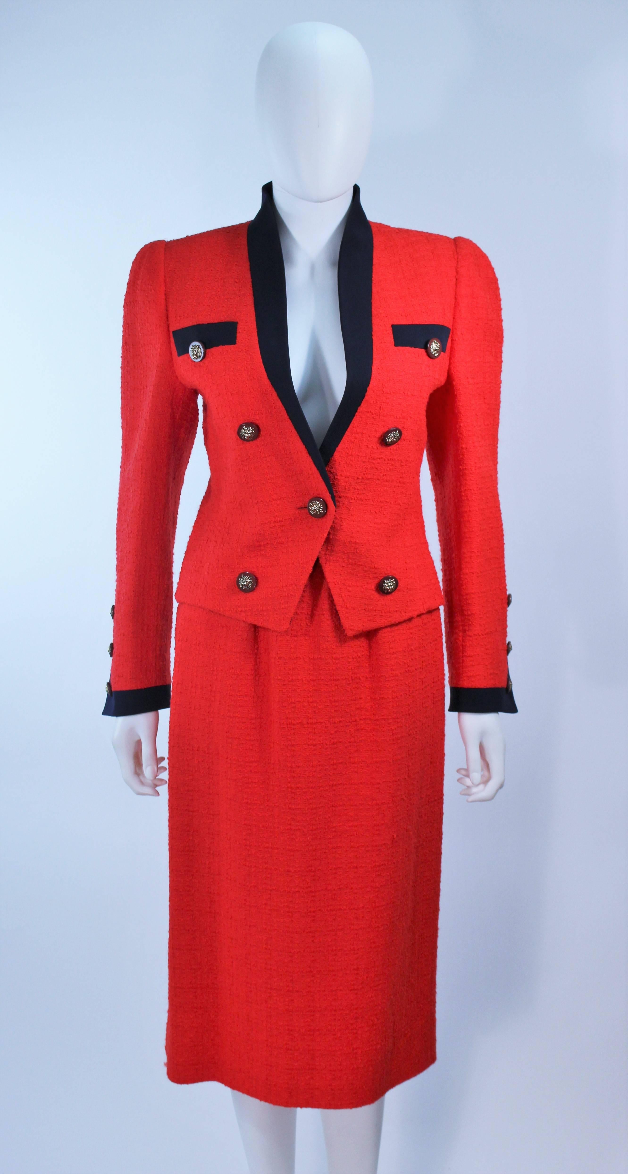  This suit is composed of a red boucle with black trim and gold buttons. Features front pockets on the jacket and side pockets on the skirt with a zipper closure. Featured in the film 