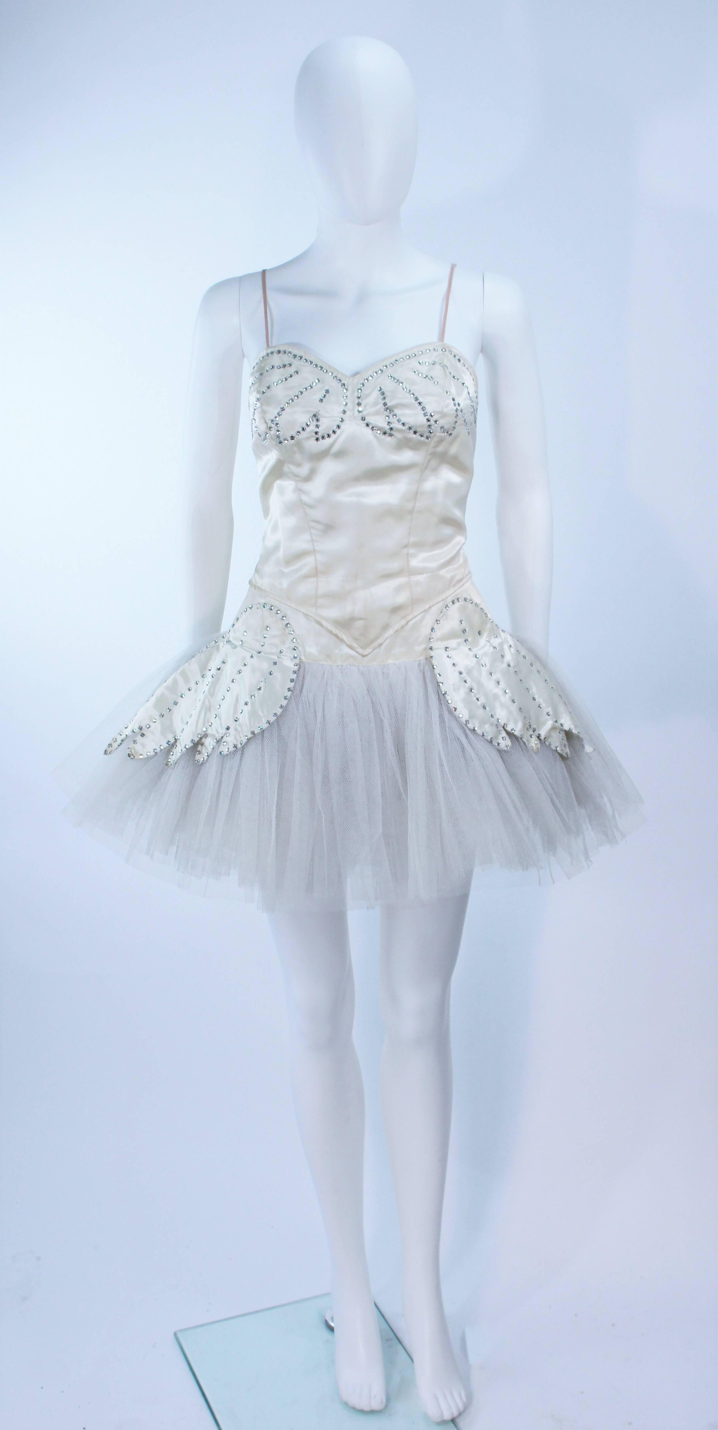  This Tutu is composed of a ivory hued satin with rhinestone applique and tulle skirt. Features a crotch interior and hook and eye closure. In good vintage condition. Some missing rhinestones (There are signs of wear dues to age and could use dry