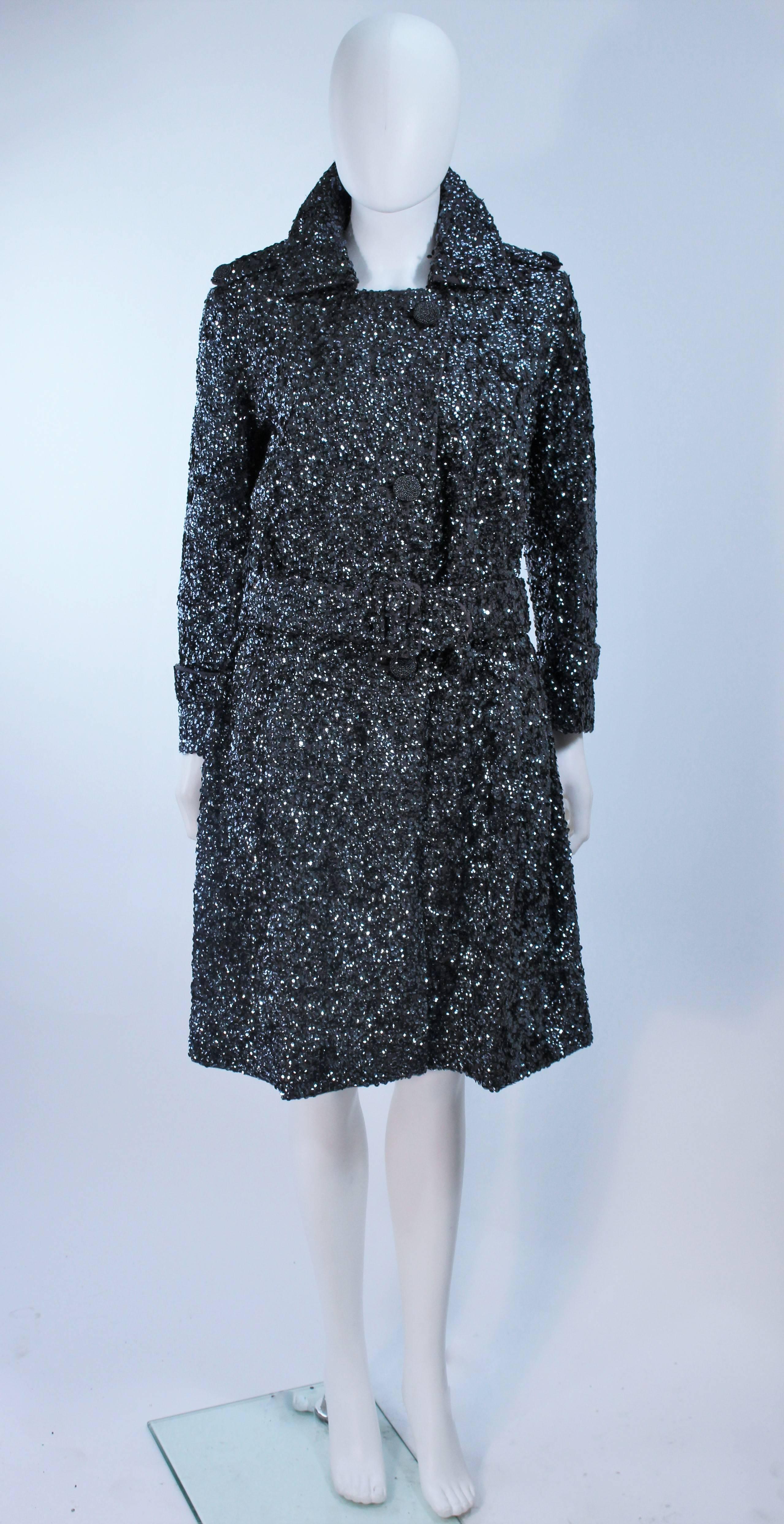  This coat is composed of a sequin wool in a silver color with gunmetal hue sequins. There are center front snap closures and the same style buttons at the shoulders as accents. A great vintage design, needs sequin restoration on the collar and