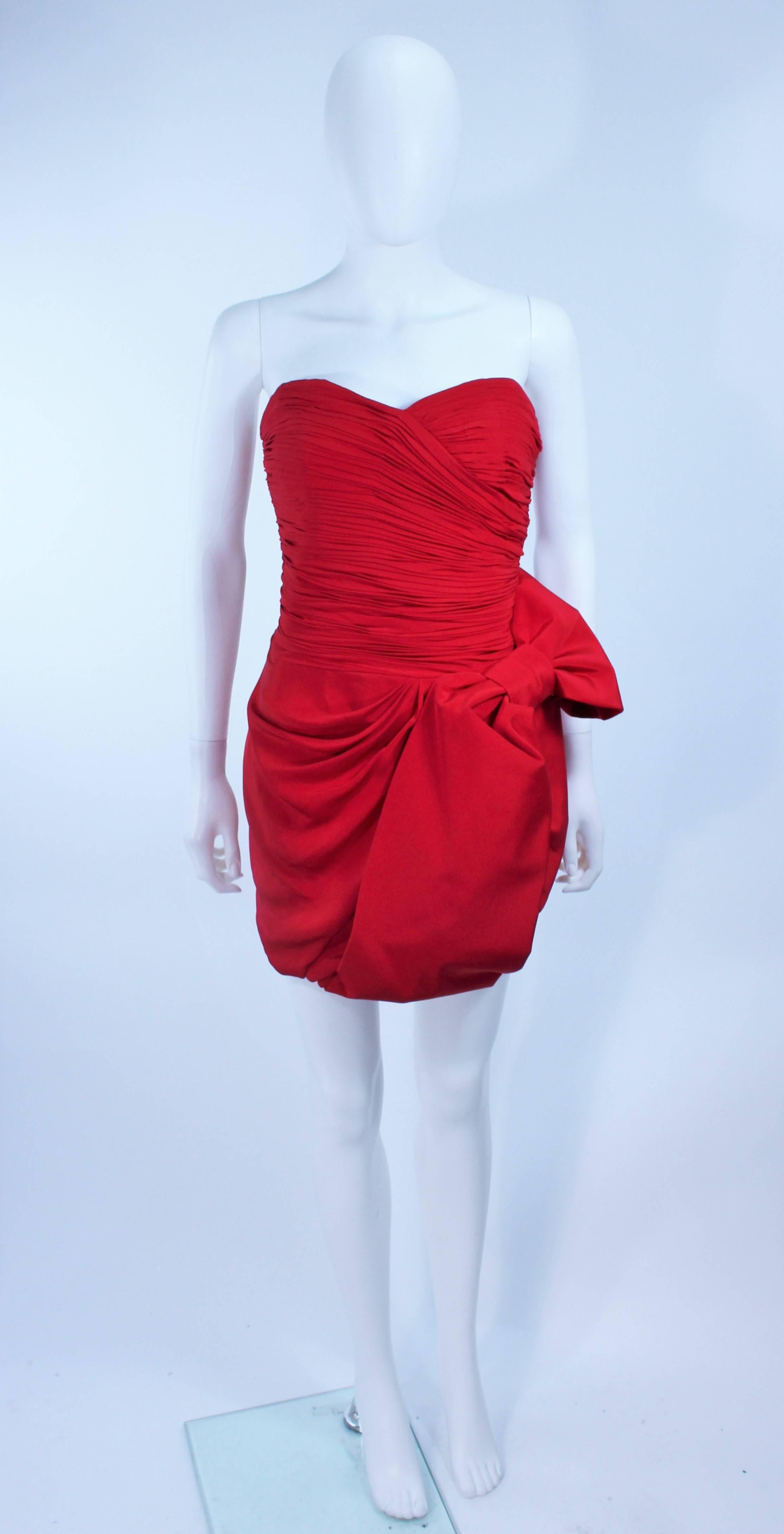 This Marchesa  cocktail dress is composed of a lipstick red fabric and features a ruched design with large bow accent. There is a center back zipper closure. In excellent condition.

  **Please cross-reference measurements for personal accuracy.