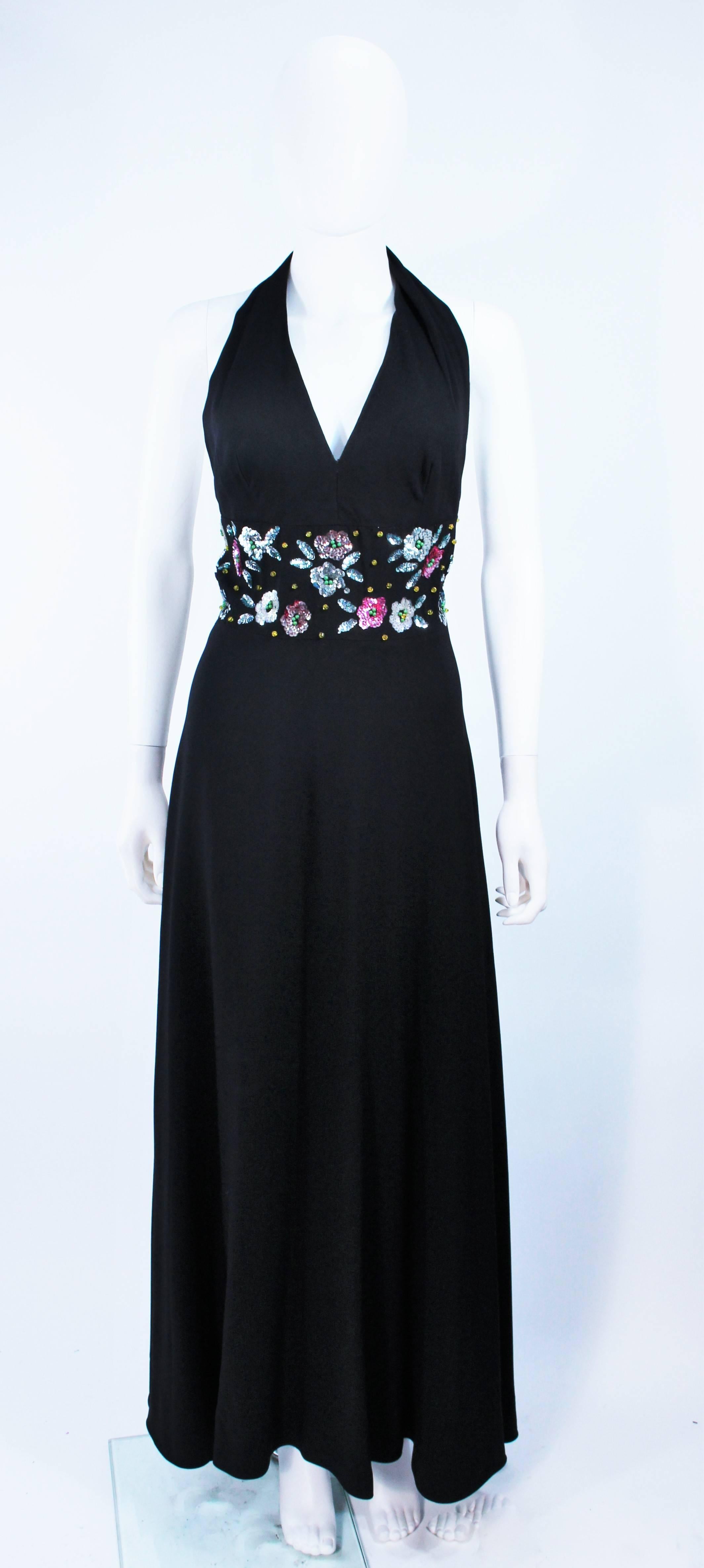 This gown is composed of a a black crepe with an embellished waist detail, featuring a floral sequin and rhinestone applique. There is a center back zipper closure. In excellent vintage condition.

  **Please cross-reference measurements for