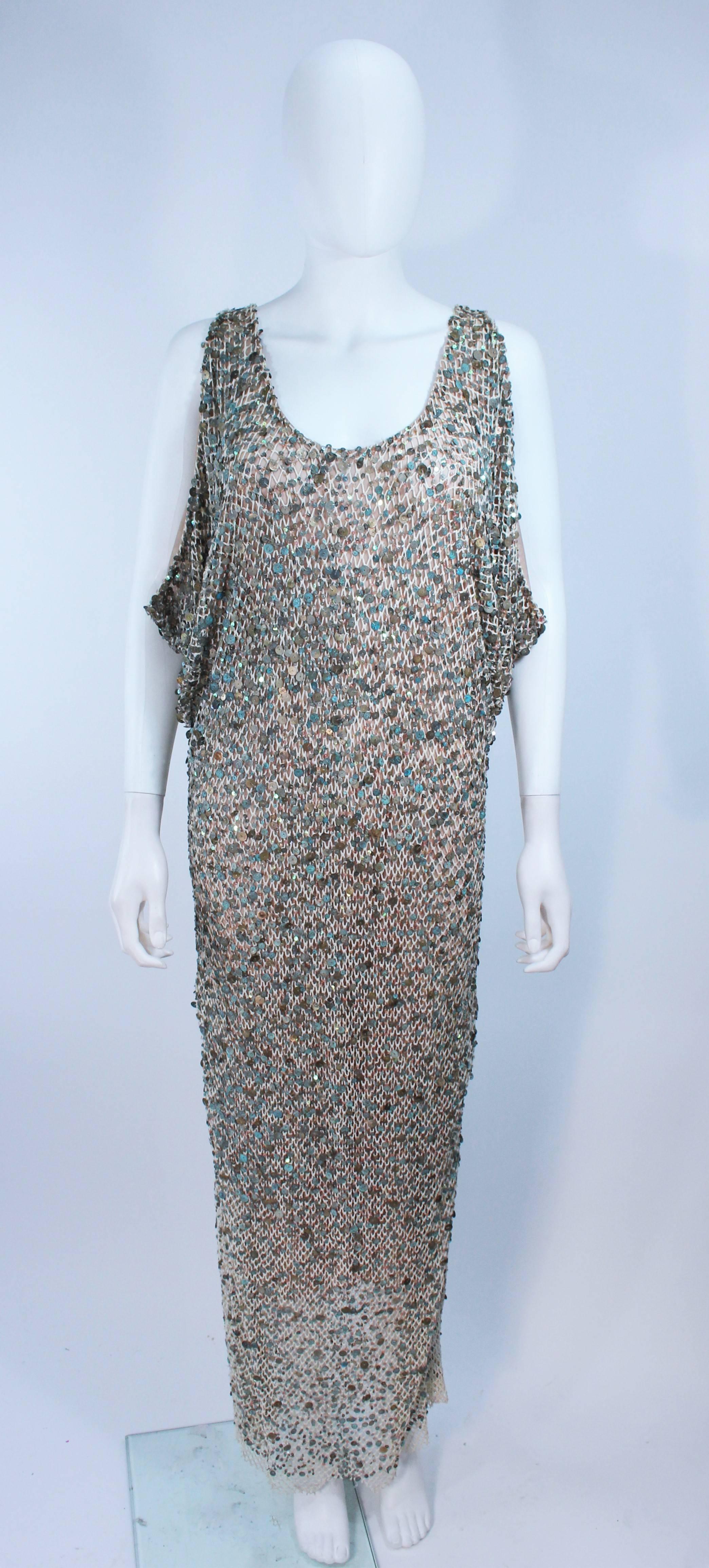 This is a Heike Jarick design. This dress is composed of a mesh layered with a thick/wide weave cotton that is embellished by weathered paillettes. The color of the embellishments range from an aqua to white and bronze. This dress has a stunning