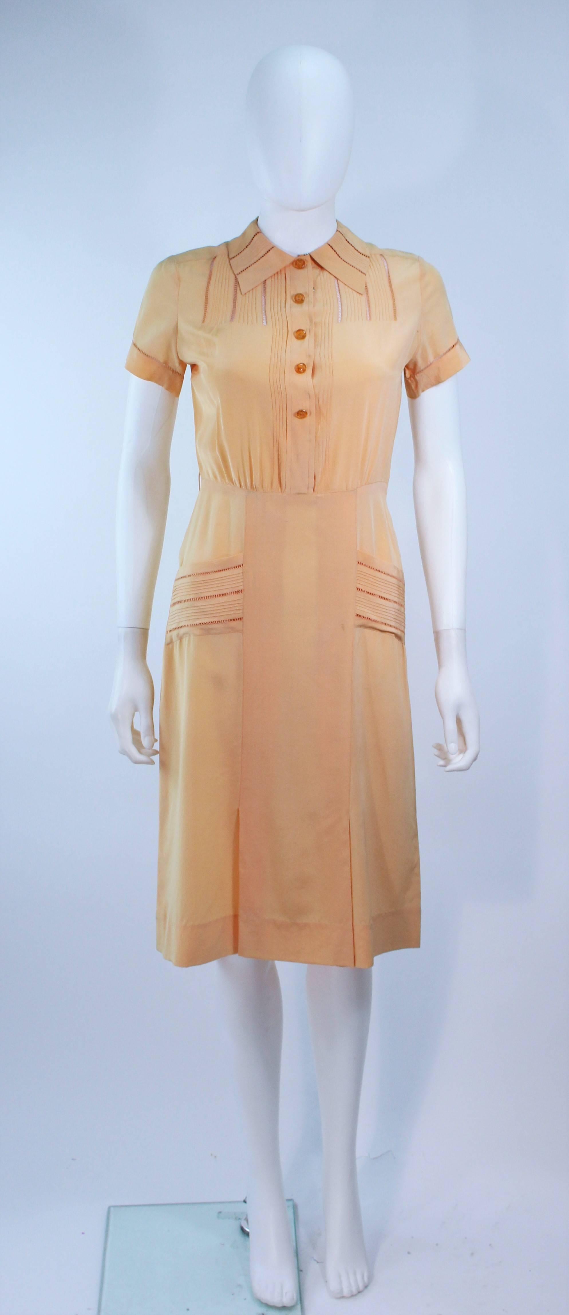 This dress is composed of an apricot hue silk. Features sheer lace inserts, front pockets, and center front buttons. In excellent vintage condition, some discoloration due to age.

**Please cross-reference measurements for personal accuracy. Size