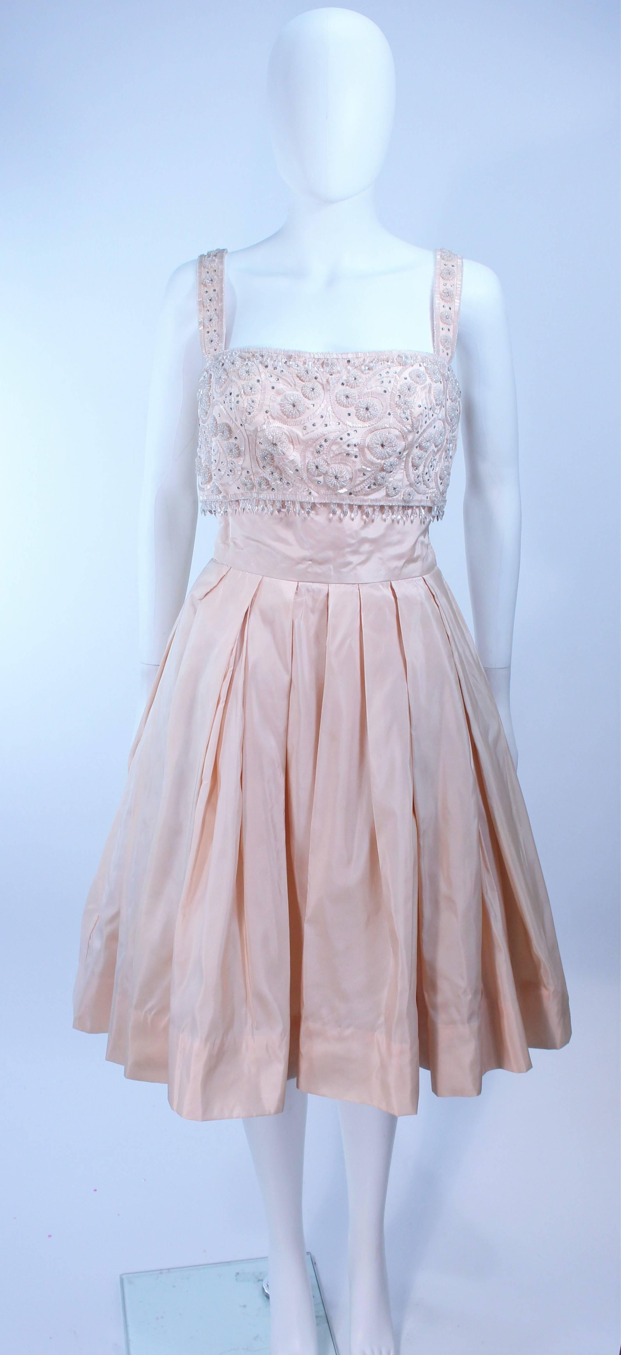 This cocktail dress is composed of a light pink embellished taffeta. Features a side zipper closure with hook and eyes. In great vintage condition, sold 
