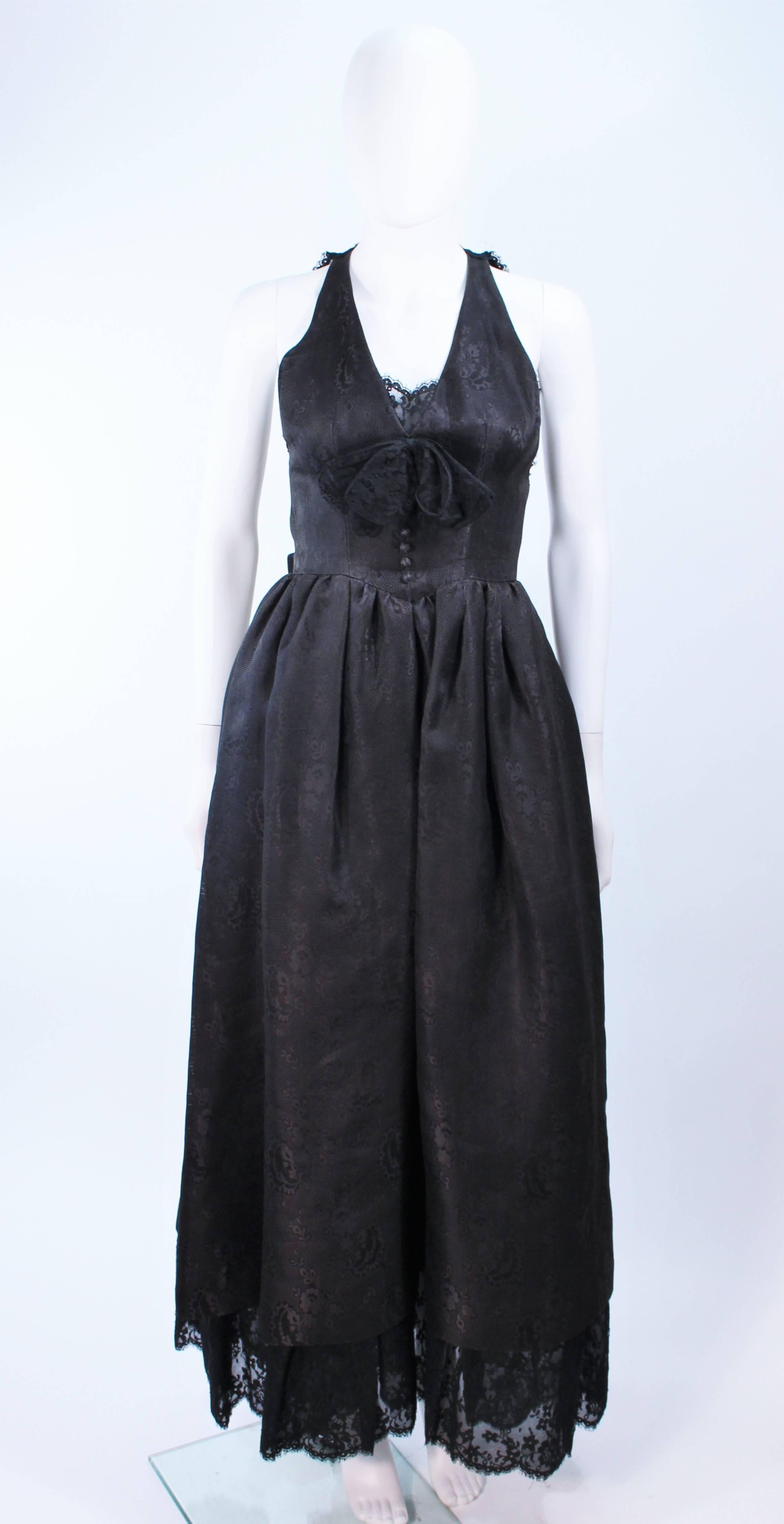 This Nina Ricci design is composed of a black brocade with lace. Features an interior crinoline skirt and lace halter backing. In excellent vintage condition. Due to the petite nature of this item the back is not completely zipped to the top of the