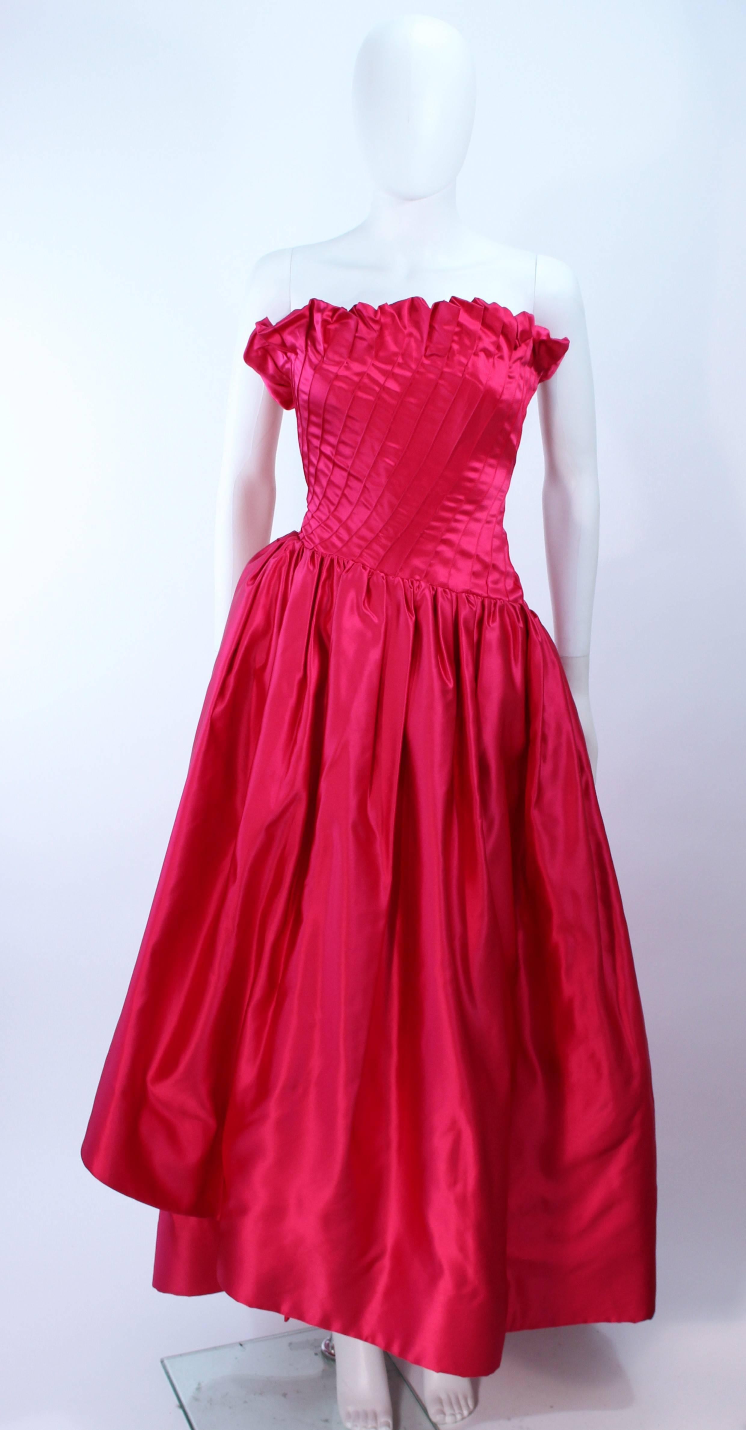 This Arnold Scaasi gown is composed of a fuchsia silk with a pintuck and draped design. Features a ruffled edge at the bust. There is a zipper closure with interior boning. In excellent vintage condition.

**Please cross-reference measurements for