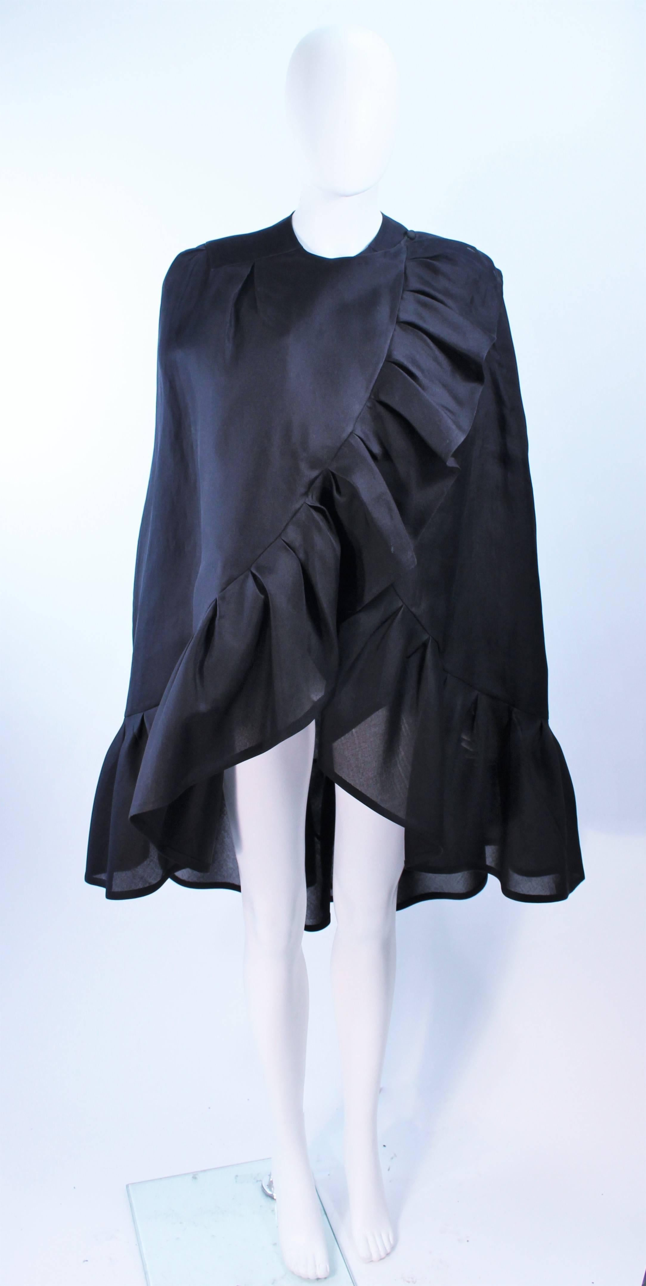 This Andre Laug cape is composed of a black silk and features a ruffle trim. There are center front snap closures and a button at the shoulder. In excellent vintage condition.

**Please cross-reference measurements for personal