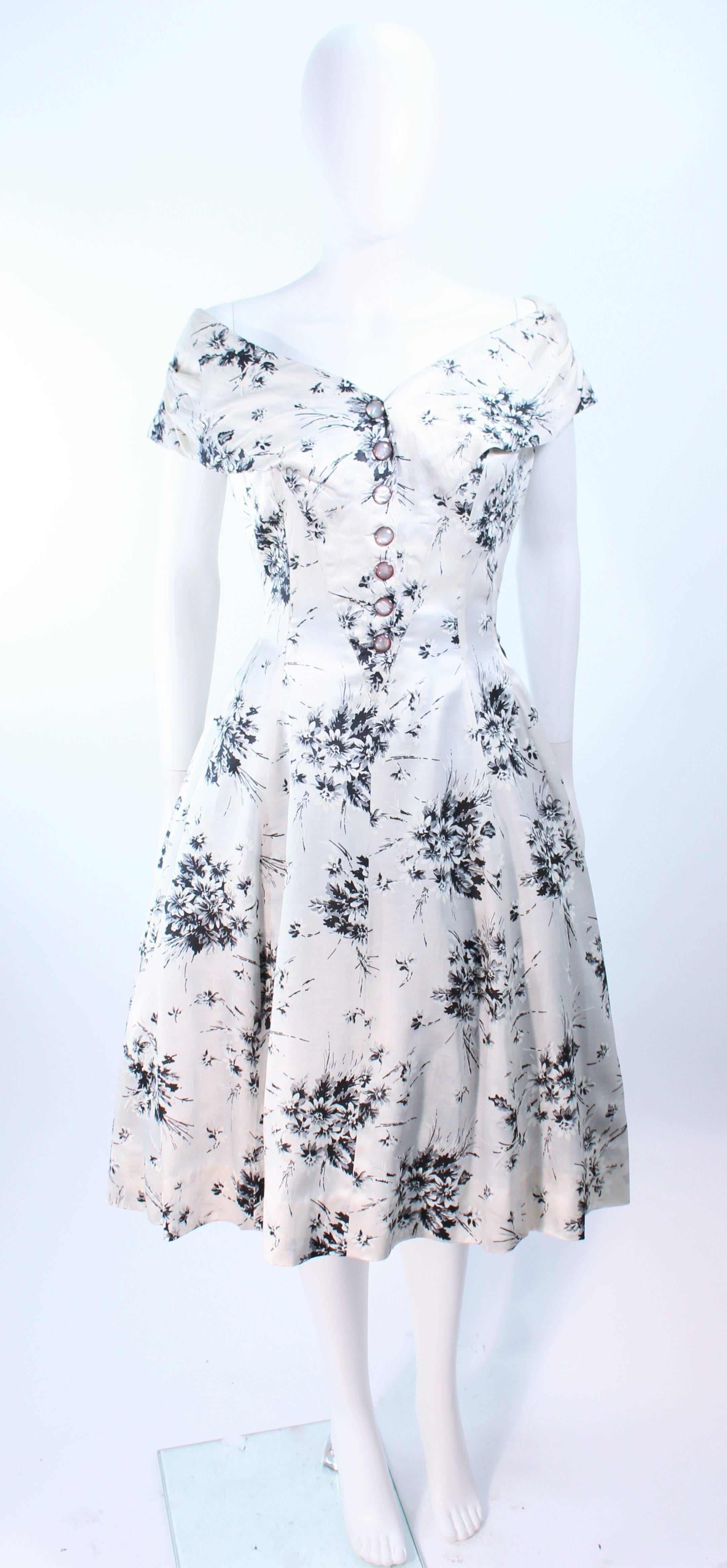 This cocktail dress is composed of a printed silk with a watercolor pattern in hues of black, white, and grey. Features center front button closures, as well as a side zipper. Shot with crinoline (sold separately). In excellent vintage