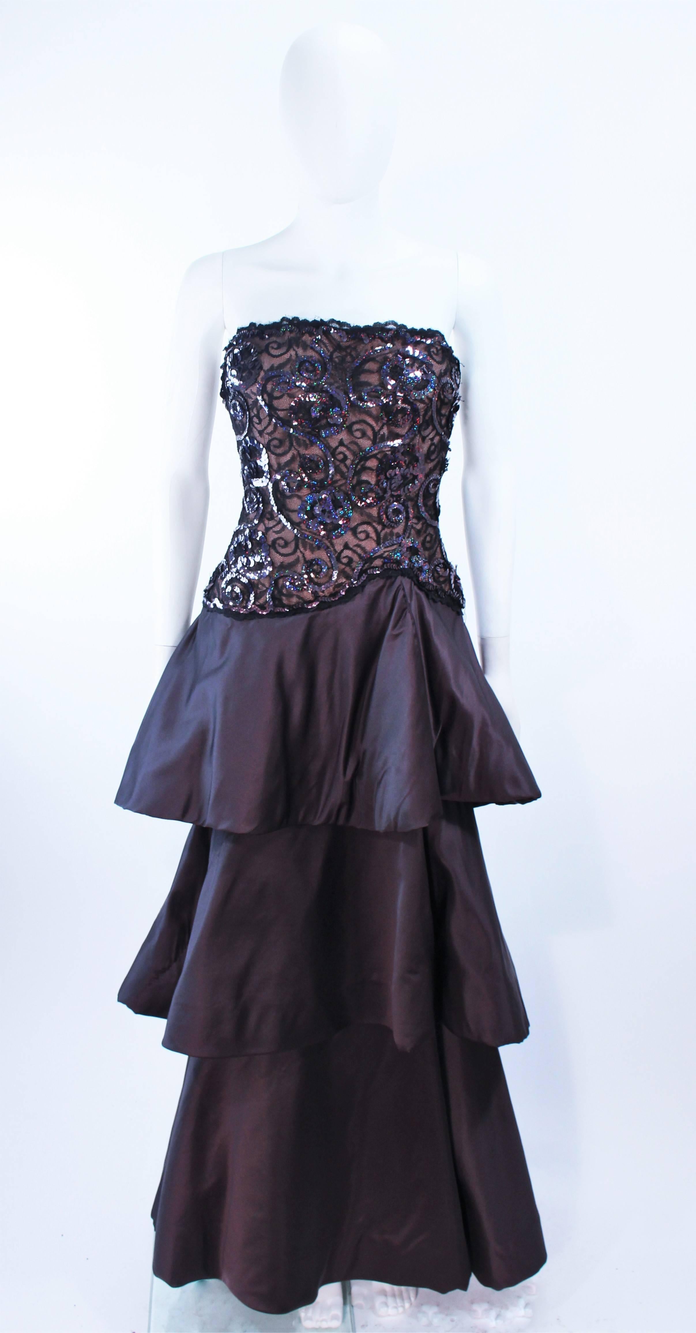 This Scaasi design is composed of black satin. Features a lace bodice with iridescent sequin applique. The tiered style skirt has a horse hair trim. There is an boned interior and a center back zipper closure. In excellent vintage