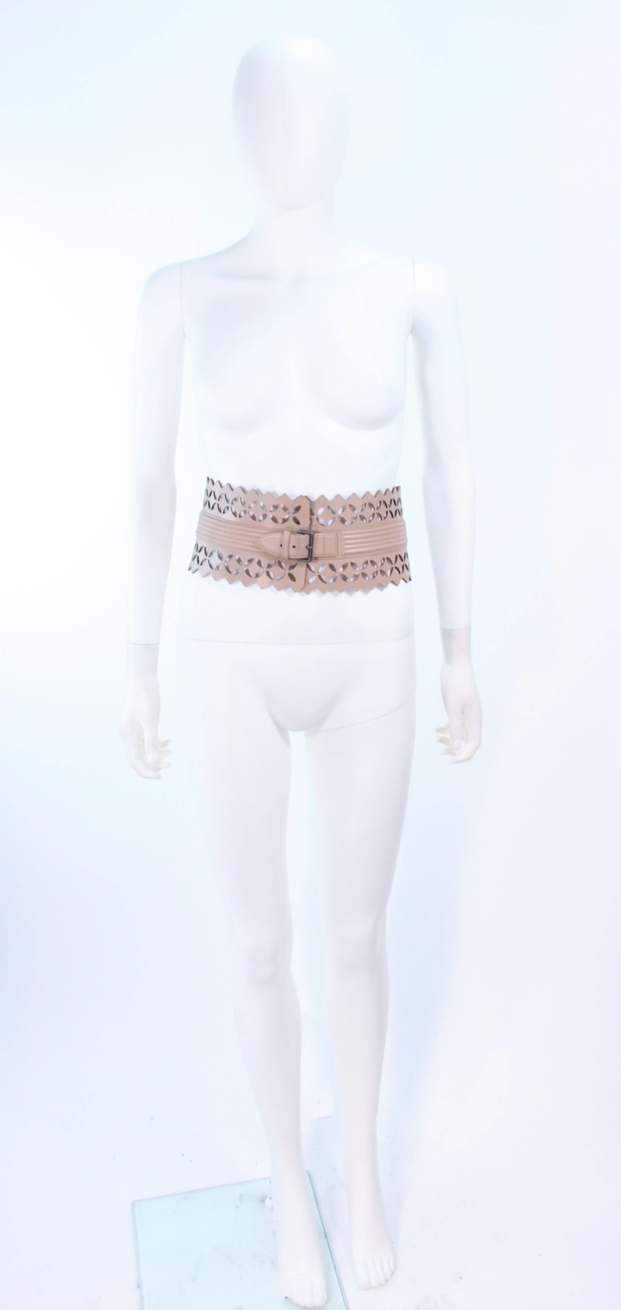 This Alaia belt is composed of a nude leather with a laser cut detailing. Features a center front adjustable buckle. In excellent pre-owned condition, slight signs of wear.

**Please cross-reference measurements for personal accuracy. Size in