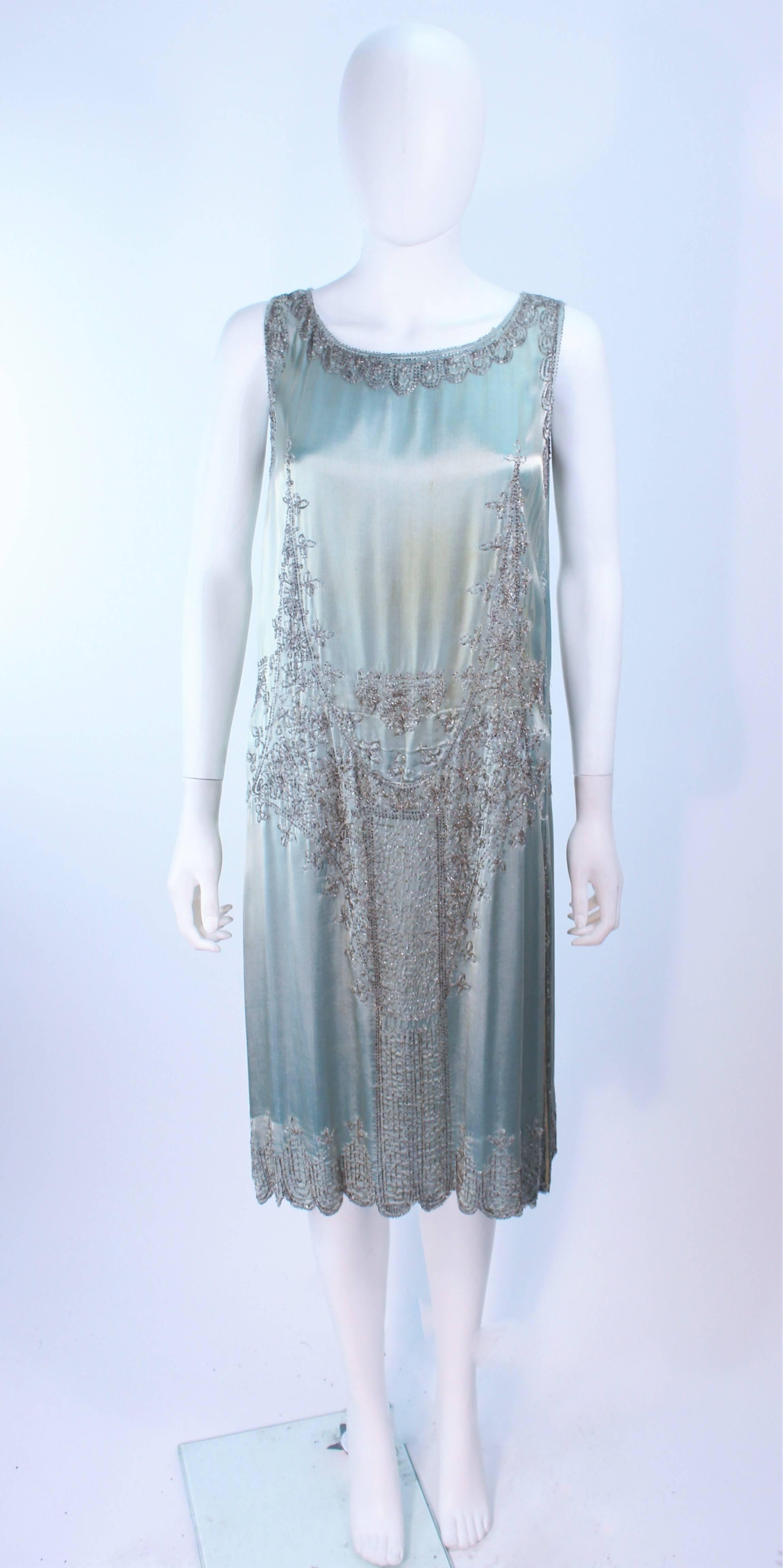 This aqua 1920's silk cocktail dress features hand beaded applique. Pull over style. In antique vintage condition, the side seams have been released to make the garment larger, there is discoloration throughout (see photos) a great period piece for