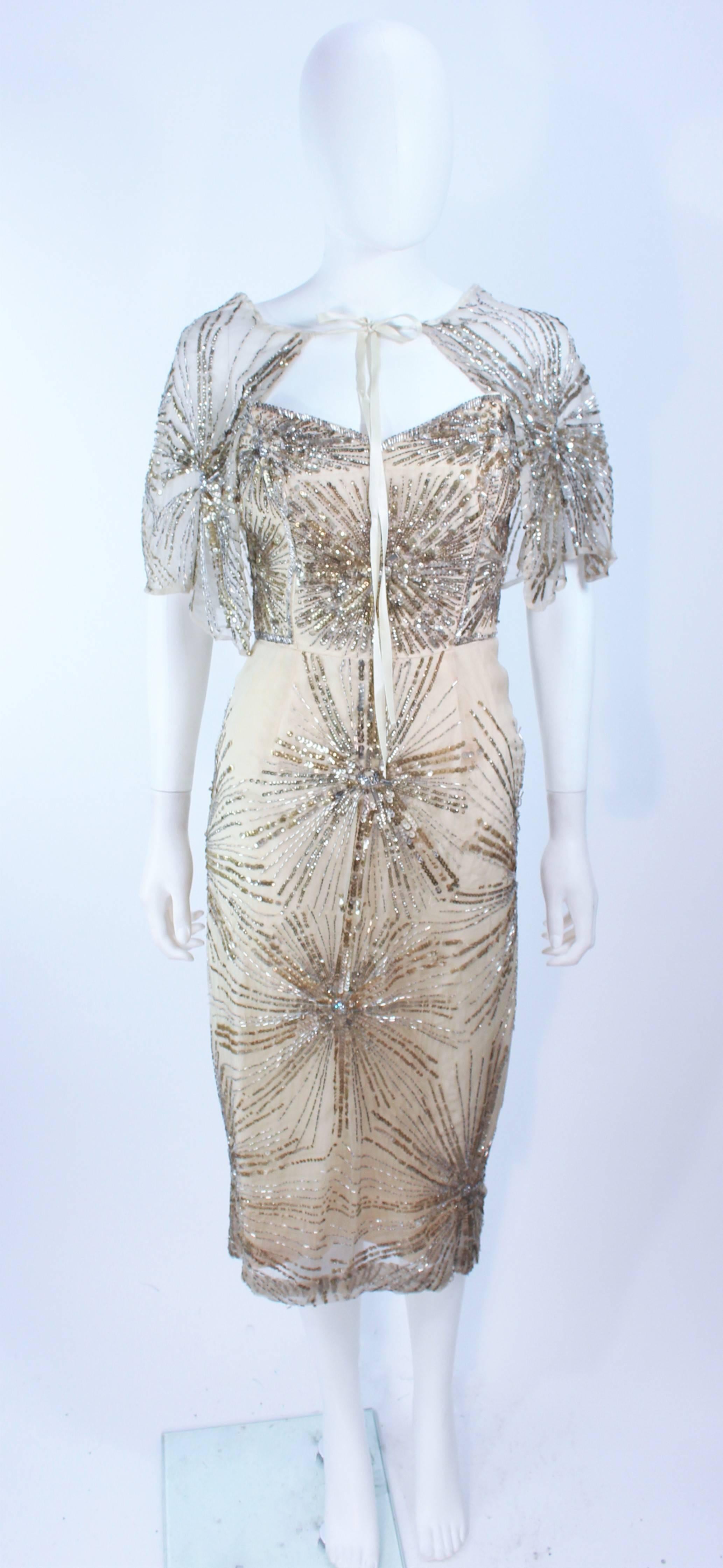 This set is composed of a beaded and sequin appliqued ivory hue silk. Features a caplet with silk ties and a pointed slim silhouette design cocktail dress. There is a side zipper closure. An excellent design in antique vintage condition, there is