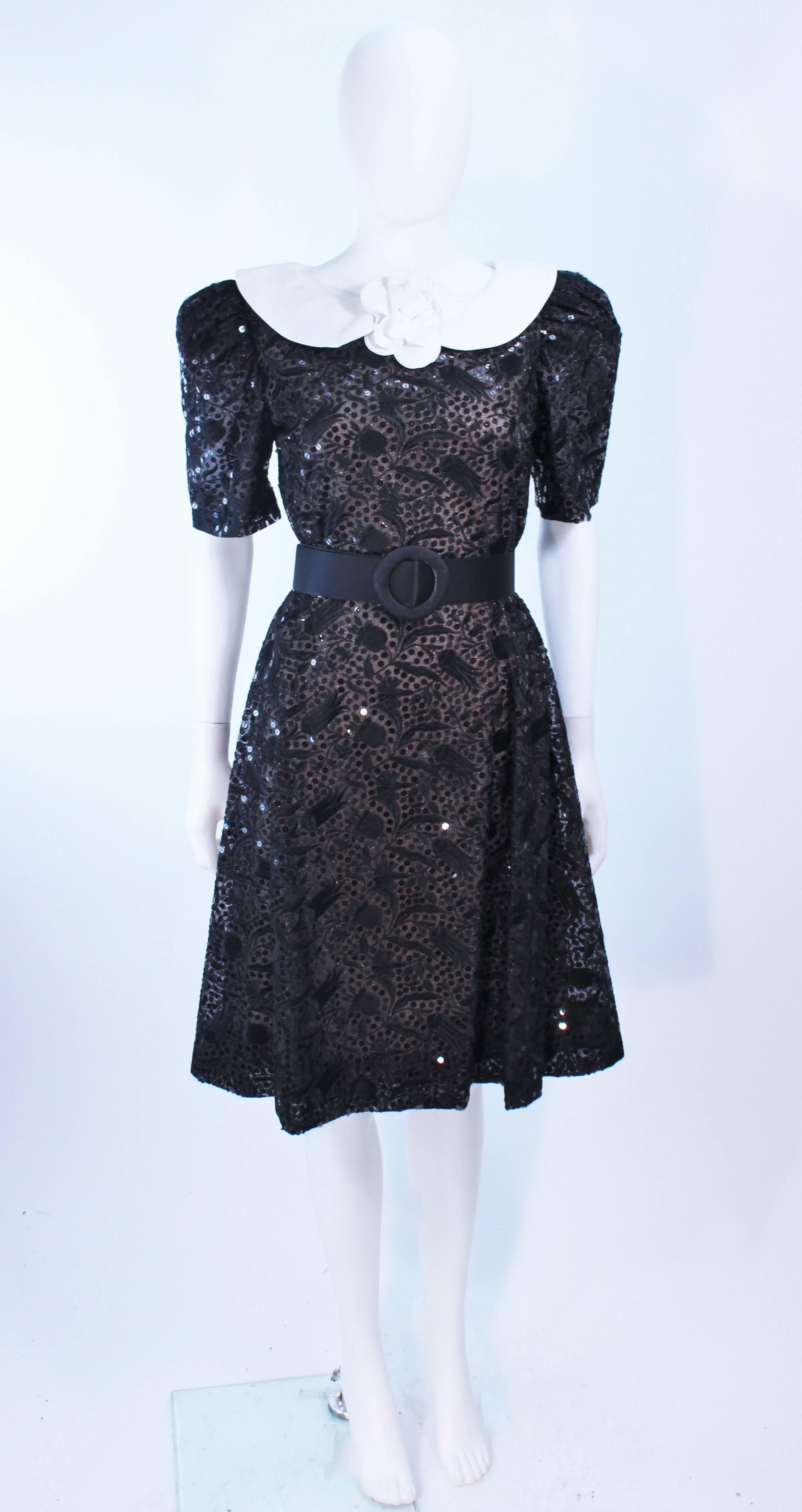 This  Arnold Scaasi custom ordered cocktail dress is composed of European black lace with sequin embellishment. 
This cocktail dress was a custom order made in the New York Atelier of Arnold Scassi for our client. 
The dress features a center back