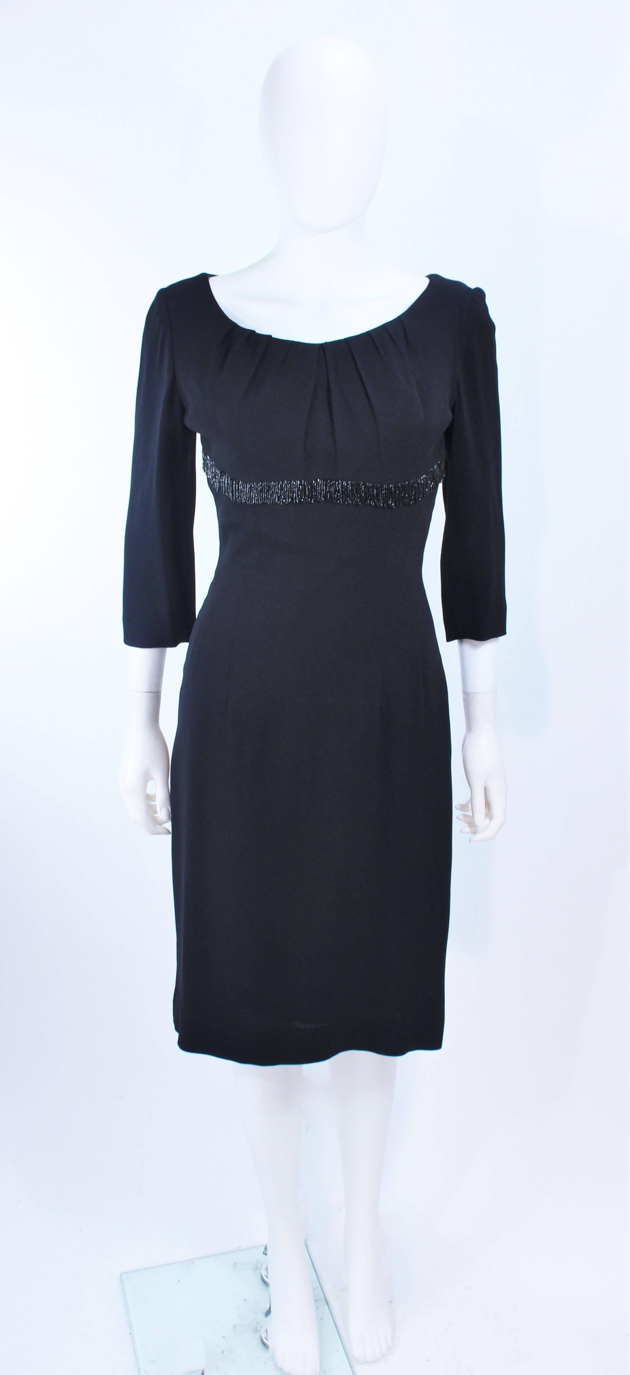 This Kat Dauzig design is composed of a black silk crepe with a beaded empire waist detail. Features 3/4 length sleeves with a pleated round collar. There is a zipper closure. In excellent vintage condition.

**Please cross-reference measurements
