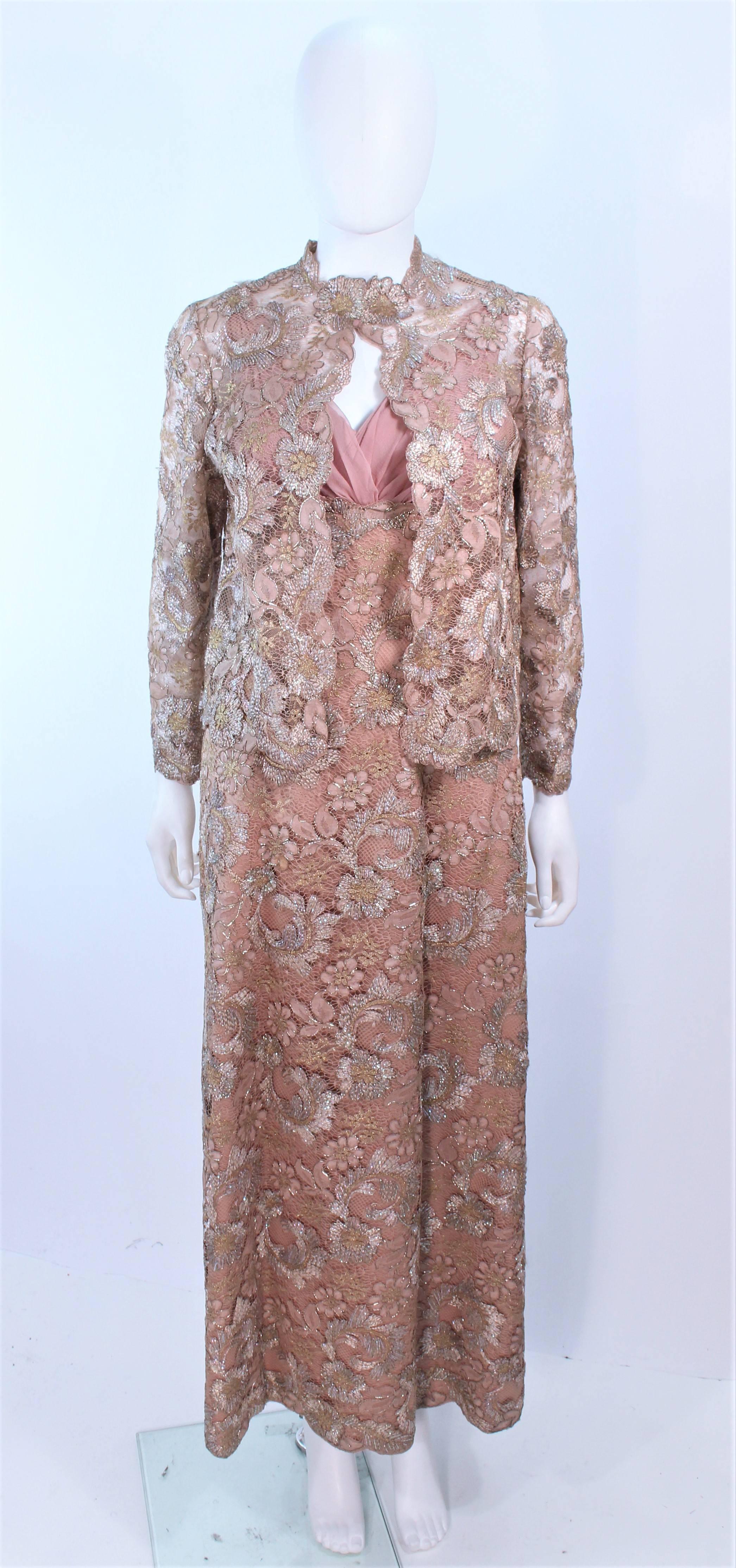 This vintage design is composed of a peach hue lace with iridescent accenting throughout. The dress features a chiffon bust with a center back zipper closure. The jacket has a center front button closure with scalloped lace edges. In excellent
