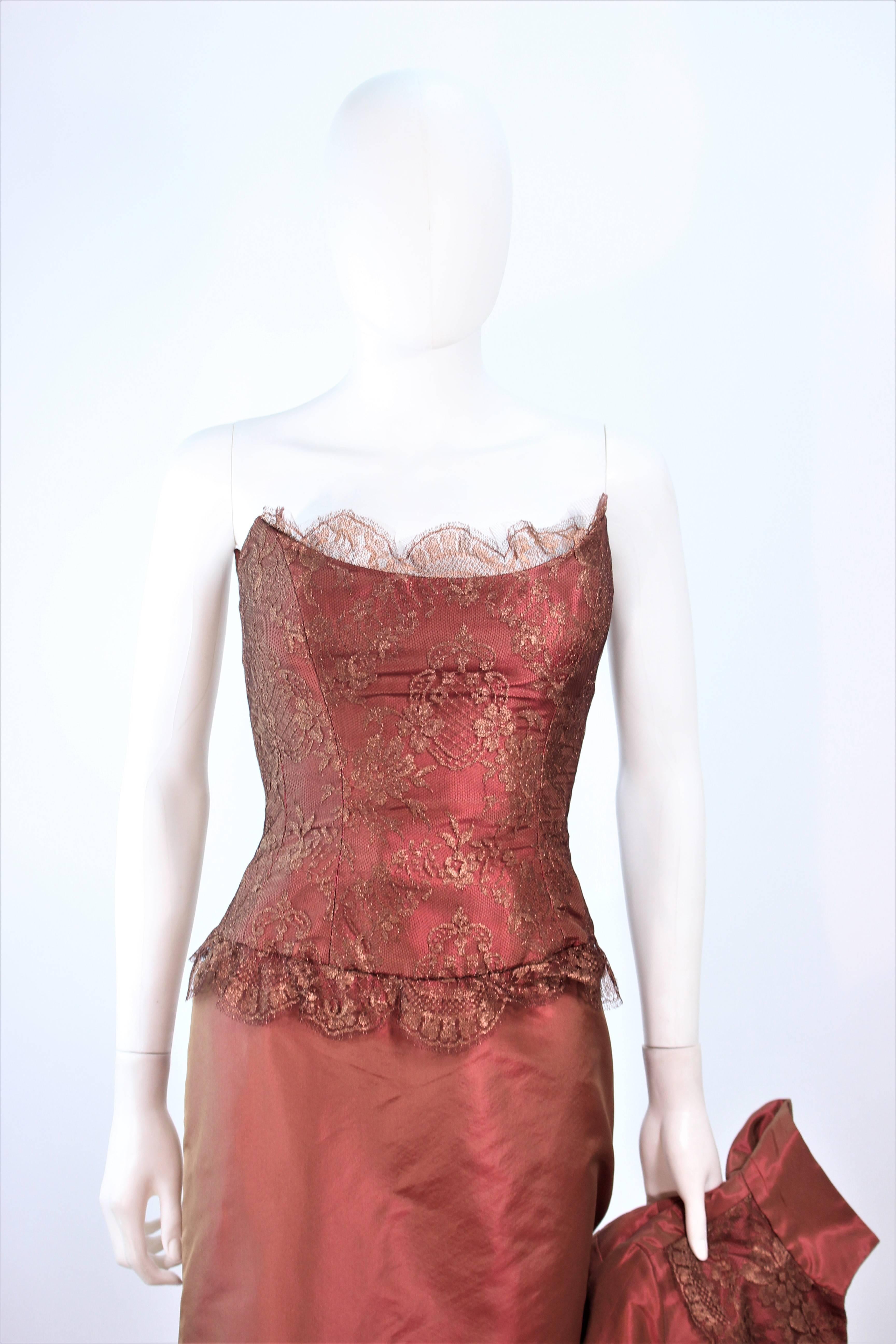 Dieses Ensemble von Elizabeth Fillmore besteht aus bronzefarbenem Satin mit metallischem Spitzenbesatz. Das Kleid ist im klassischen Stil gehalten und verfügt über ein Mieder mit Stäbchen, einen Reißverschluss in der Mitte des Rückens und einen