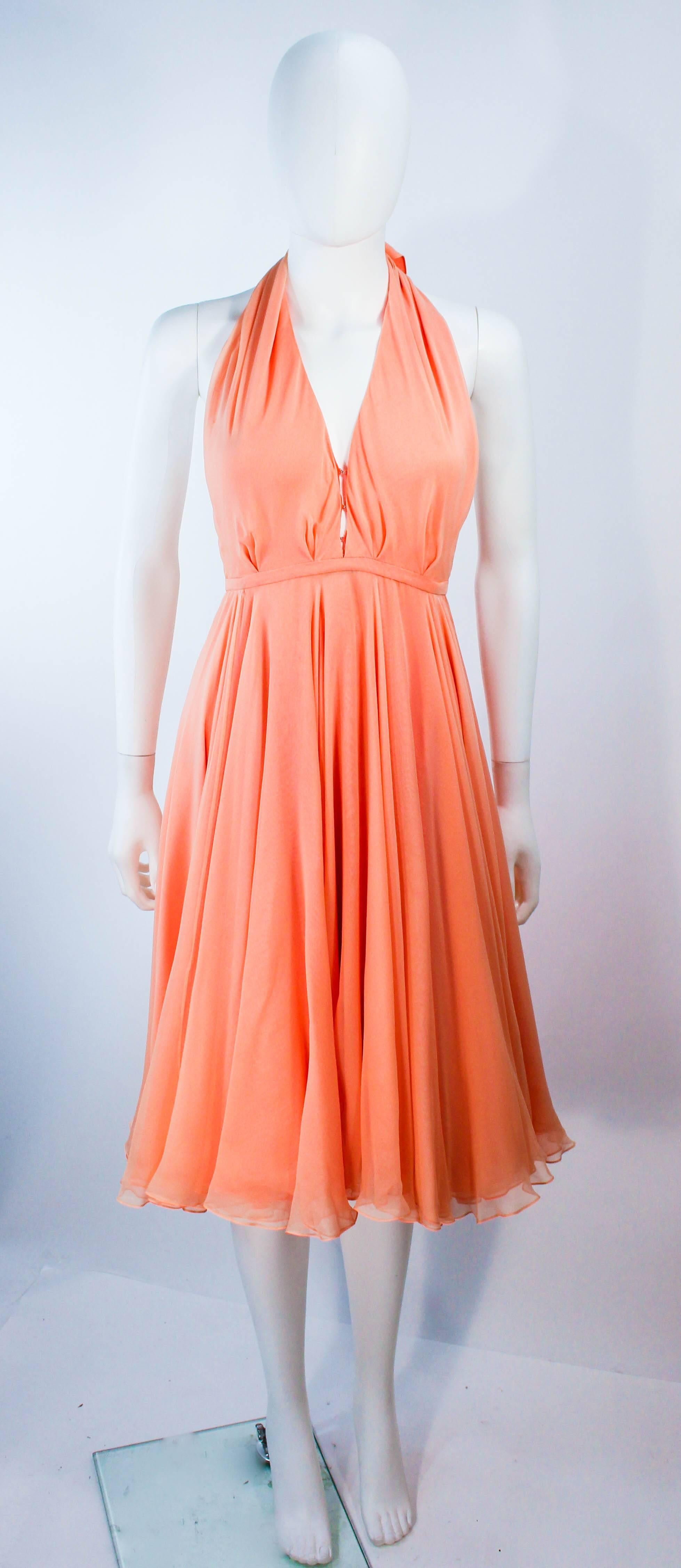 This vintage 1970's Halston cocktail dress is composed of layered silk chiffon in peach and apricot hues. There are center front hooks and center back snap closures. The long drapes can be fashioned in a variety of ways. In excellent vintage
